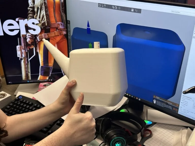 Photo of a Remnants team member holding the 3D printed garden watering can. The watering can is a beige color. Photo: Remnants Team.