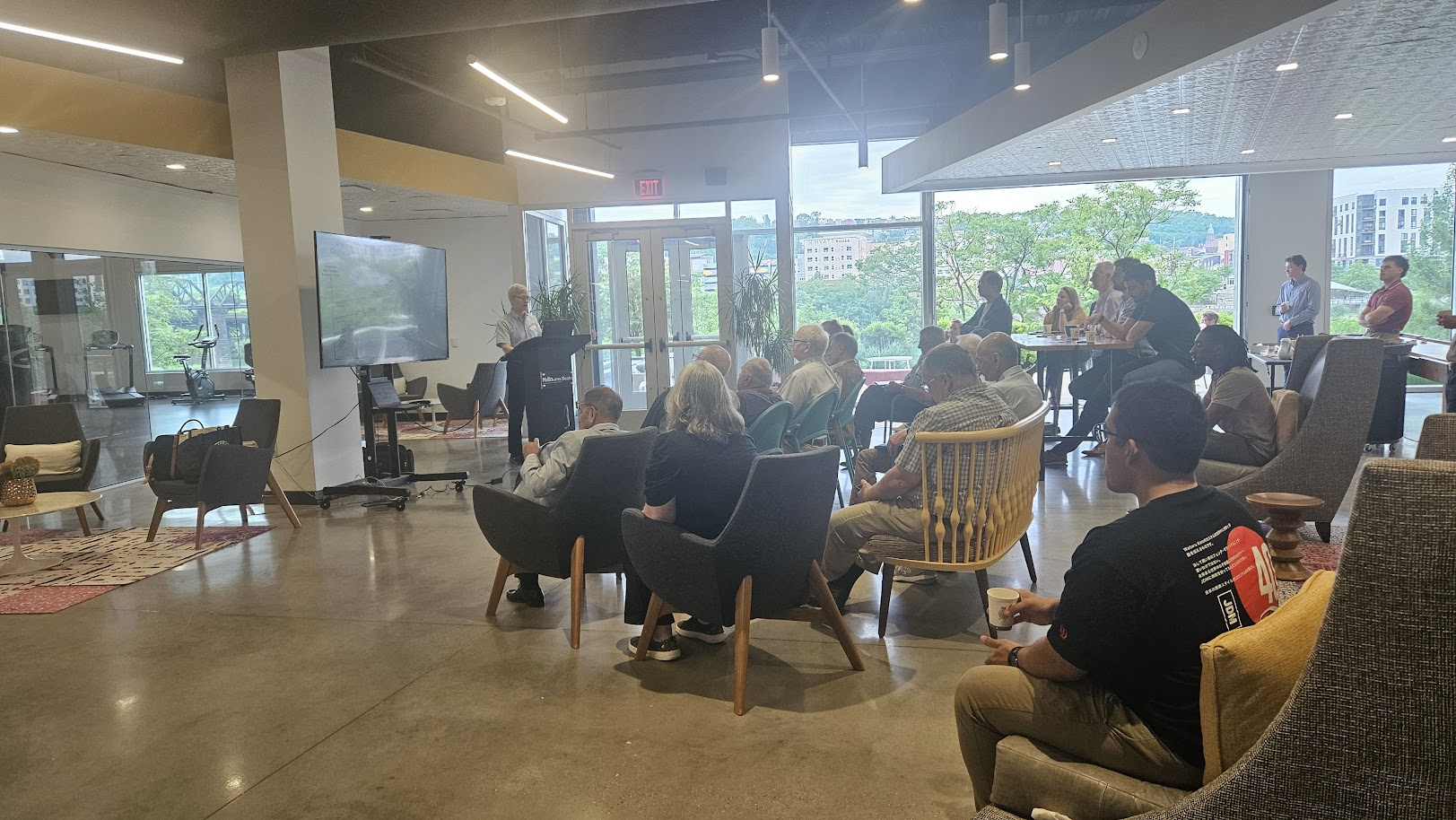 Photo of a group of people at the Hot Metal Campus Book Club. There is a presenter at a podium in front of a screen and an audience in chairs looking at the speaker.
