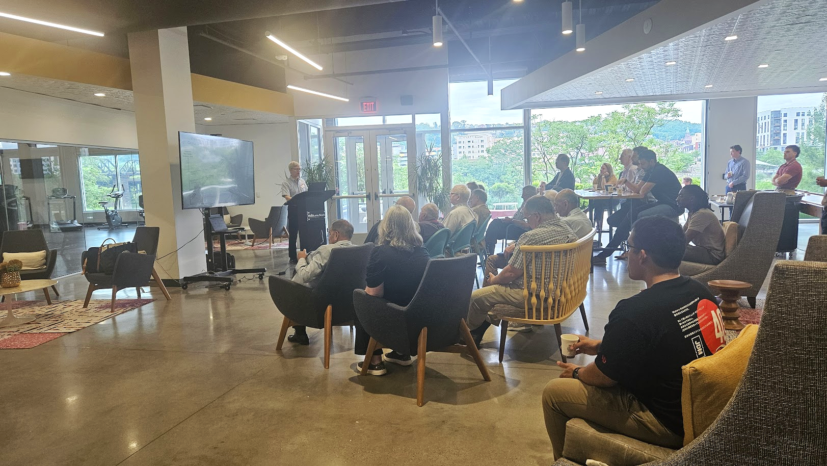 Photo of a group of people at the Hot Metal Campus Book Club. There is a presenter at a podium in front of a screen and an audience in chairs looking at the speaker.