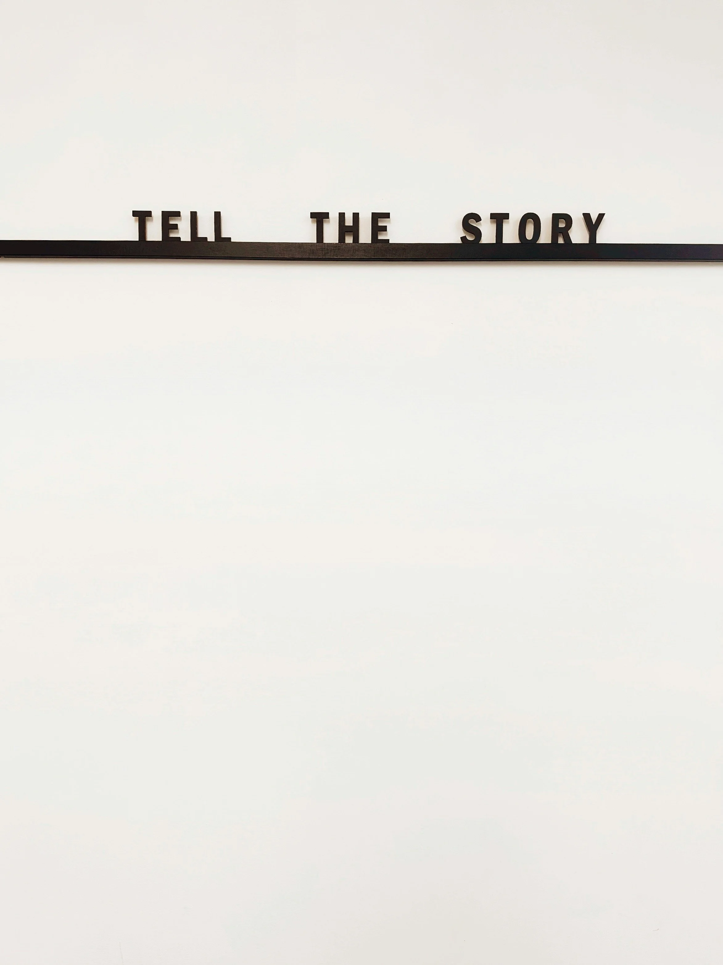 Photo Caption: Stock photo of a white background with the black letters aligned to say “Tell Your Story” aligned on a horizontal bar to hold letters. Source: Jon Tyson via Unsplash.
