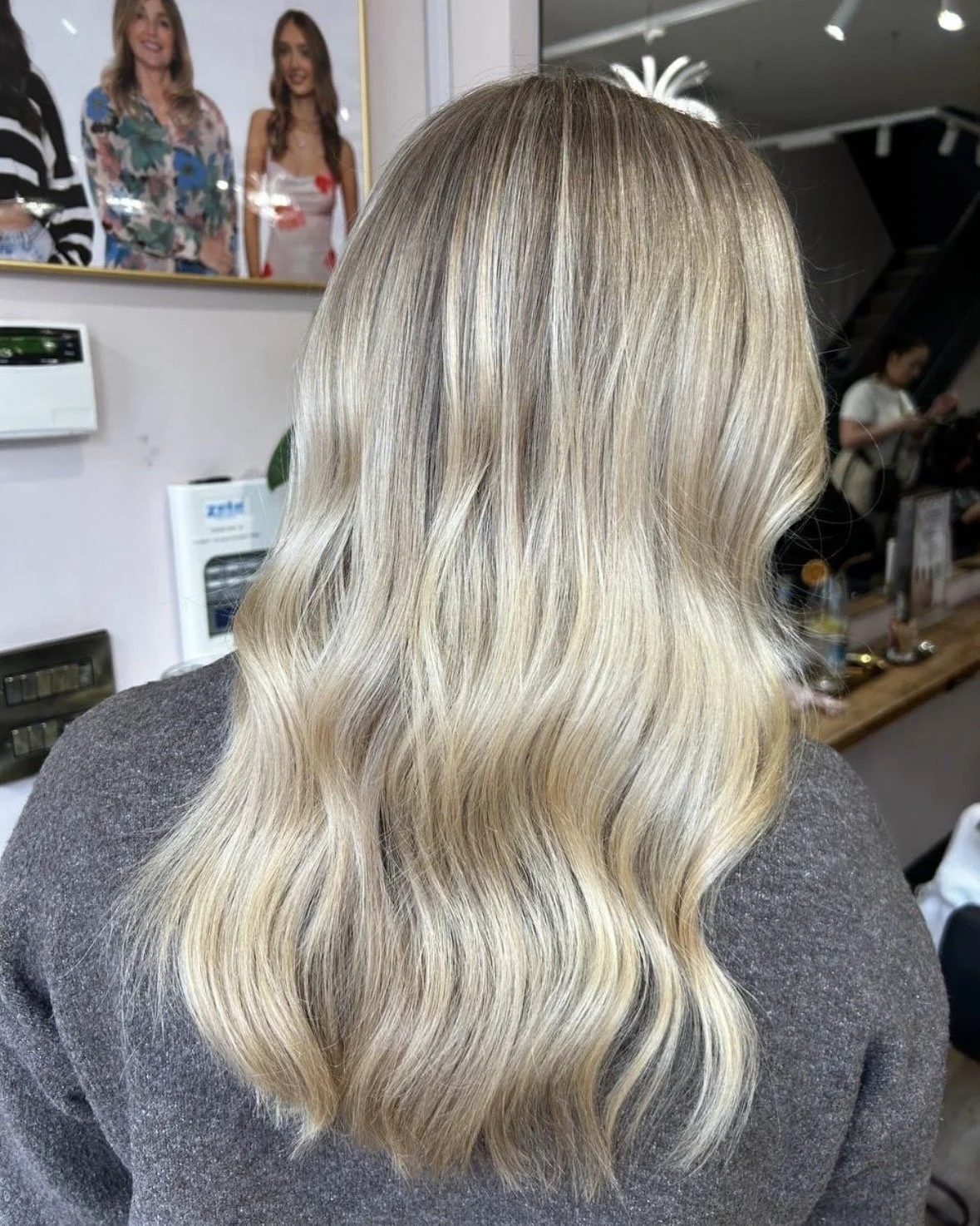 Back view of a woman with long, wavy blonde hair.