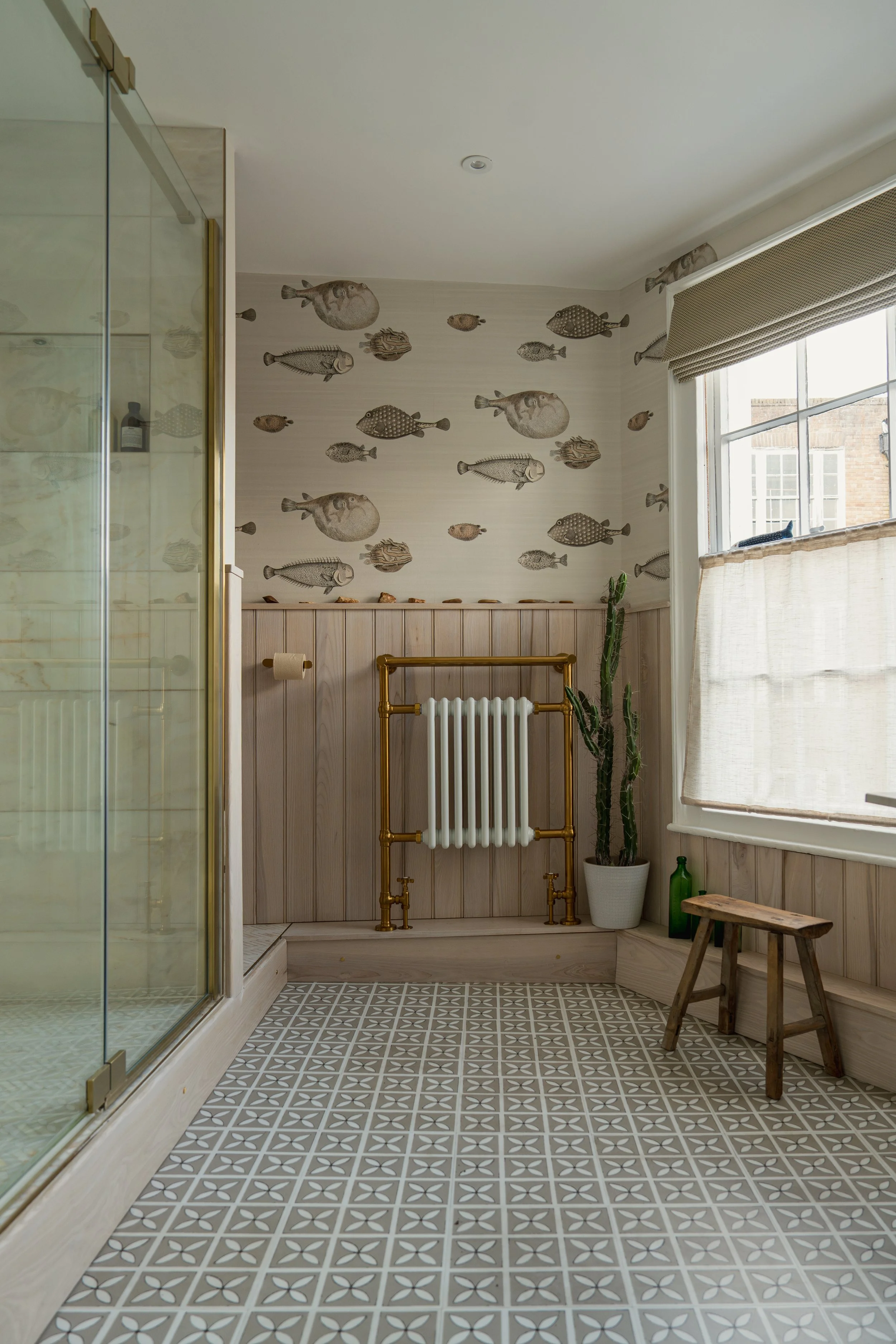 Wide view of a contemporary townhouse shower room with patterned floor tiles, brass towel radiator, walk-in shower, and layered natural textures.