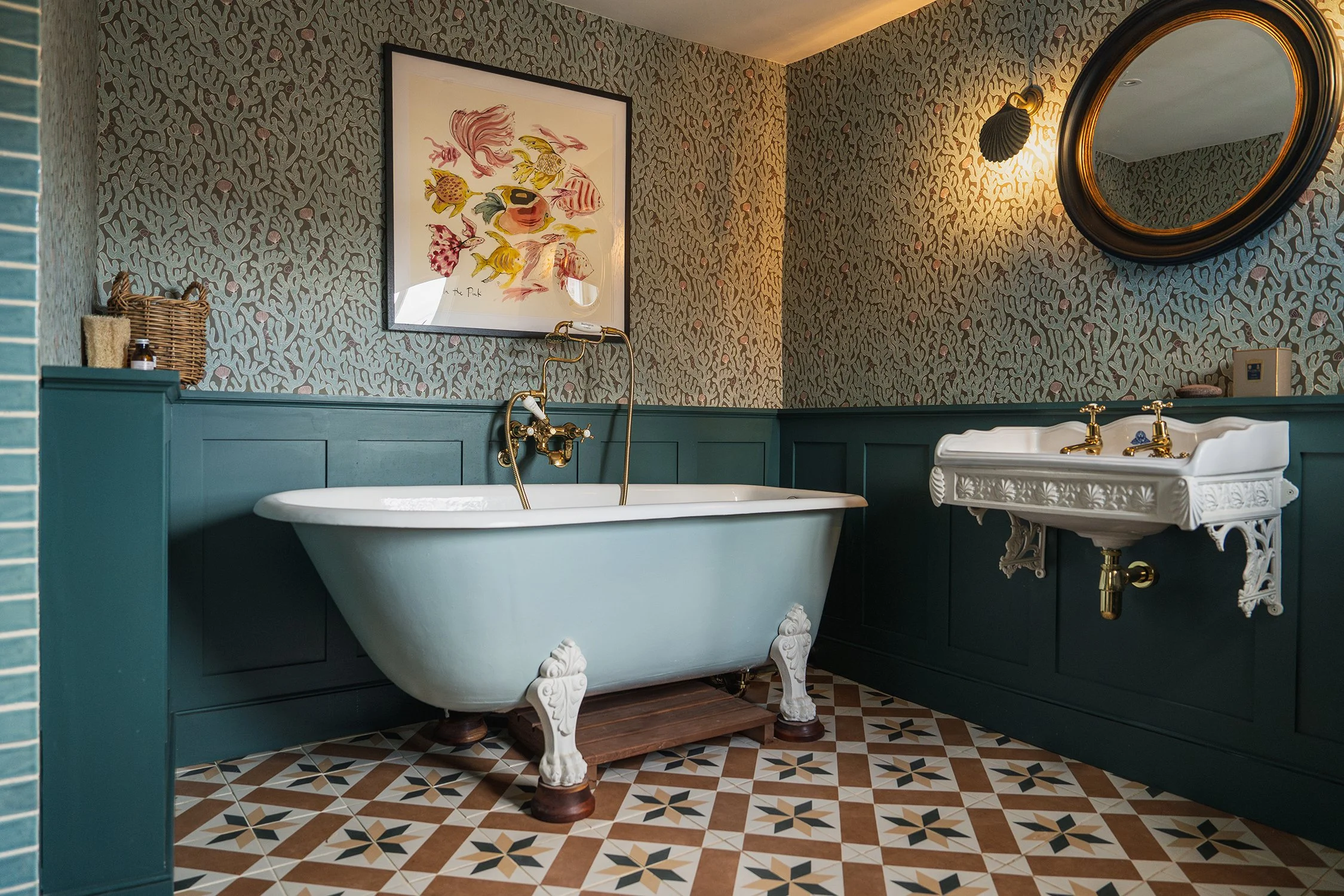 Luxury townhouse bathroom with freestanding roll-top bath, patterned floor tiles, deep teal panelling, and brass fittings inspired by heritage design.