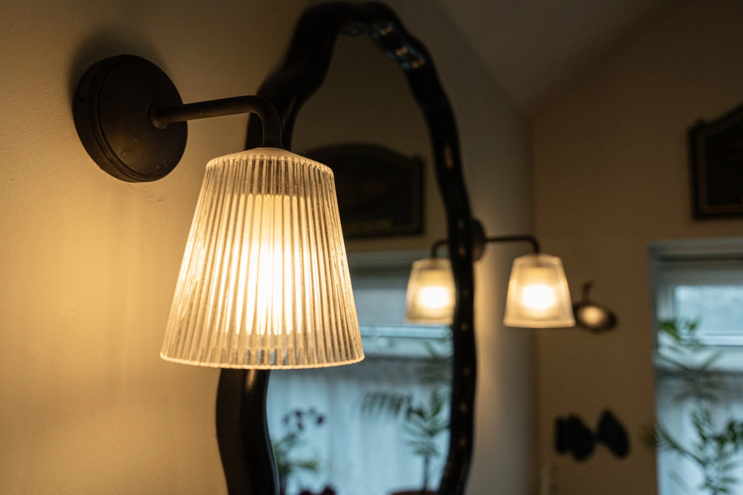 Vintage-inspired wall lights with pleated glass shades adding warm layered lighting to an elegant Edwardian bathroom interior.