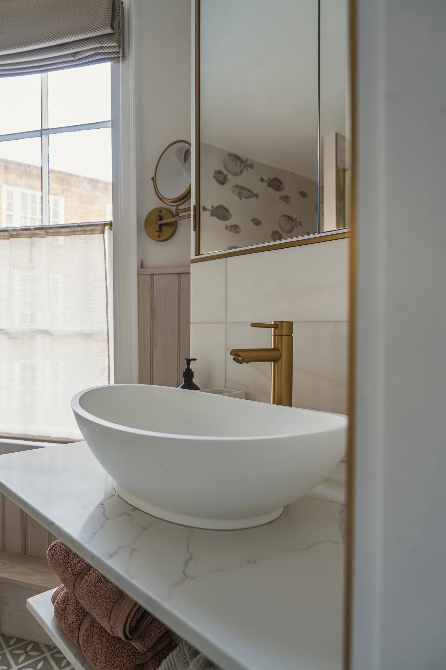 Modern bathroom vanity with marble countertop, vessel sink, brass wall tap, and soft neutral palette in a refined townhouse shower room.