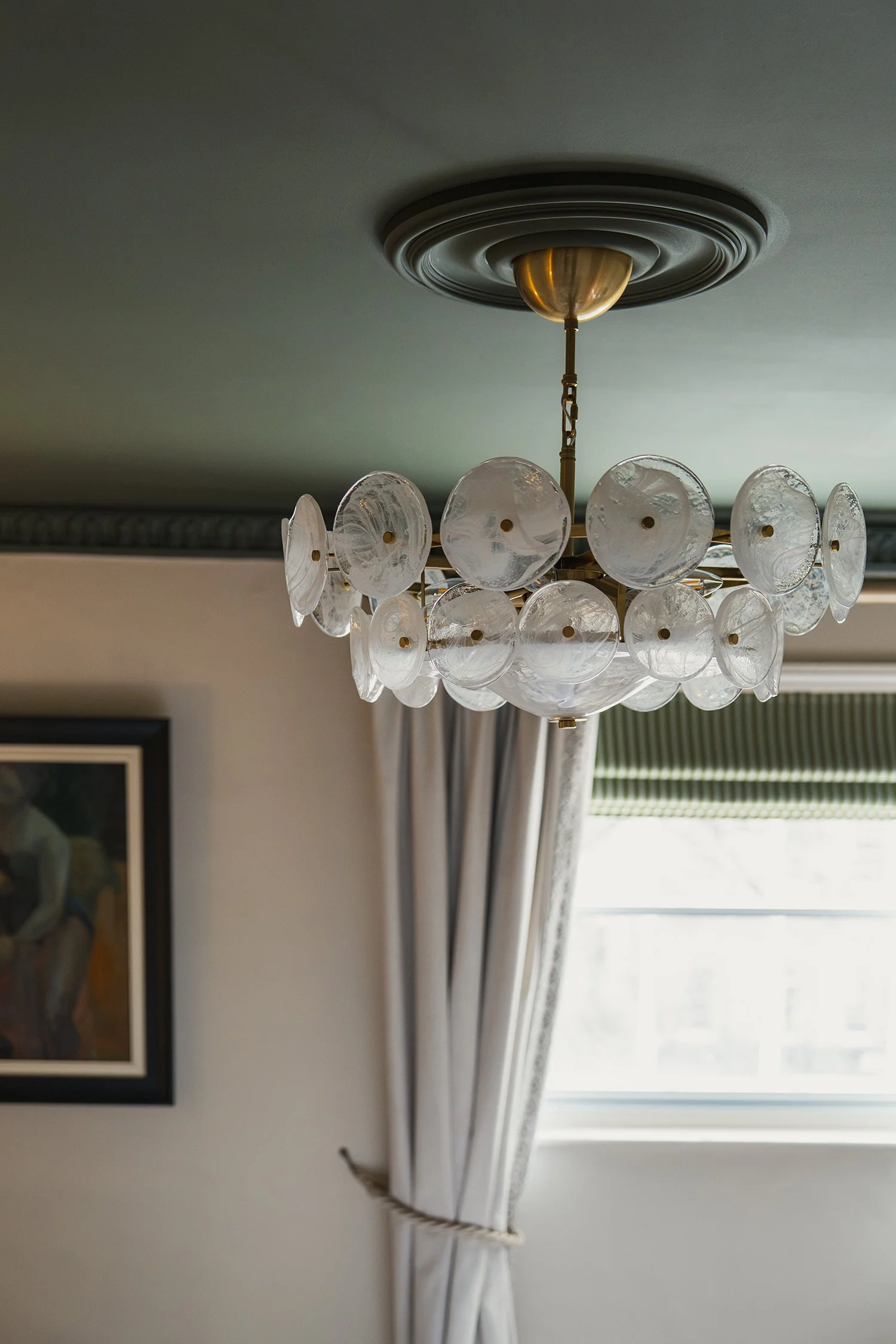 Vintage glass chandelier and soft linen curtains creating an elegant atmosphere in a thoughtfully designed townhouse guest room.