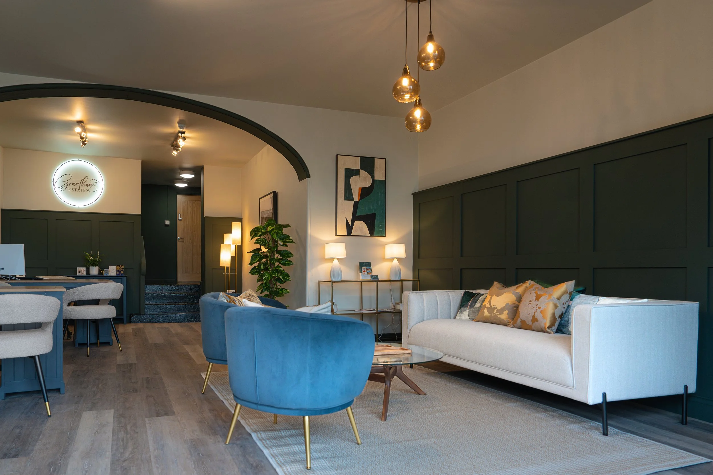 Modern estate agents office interior for Grantham's Estates featuring dark green wall panelling, contemporary seating, warm lighting, and a welcoming client reception area.