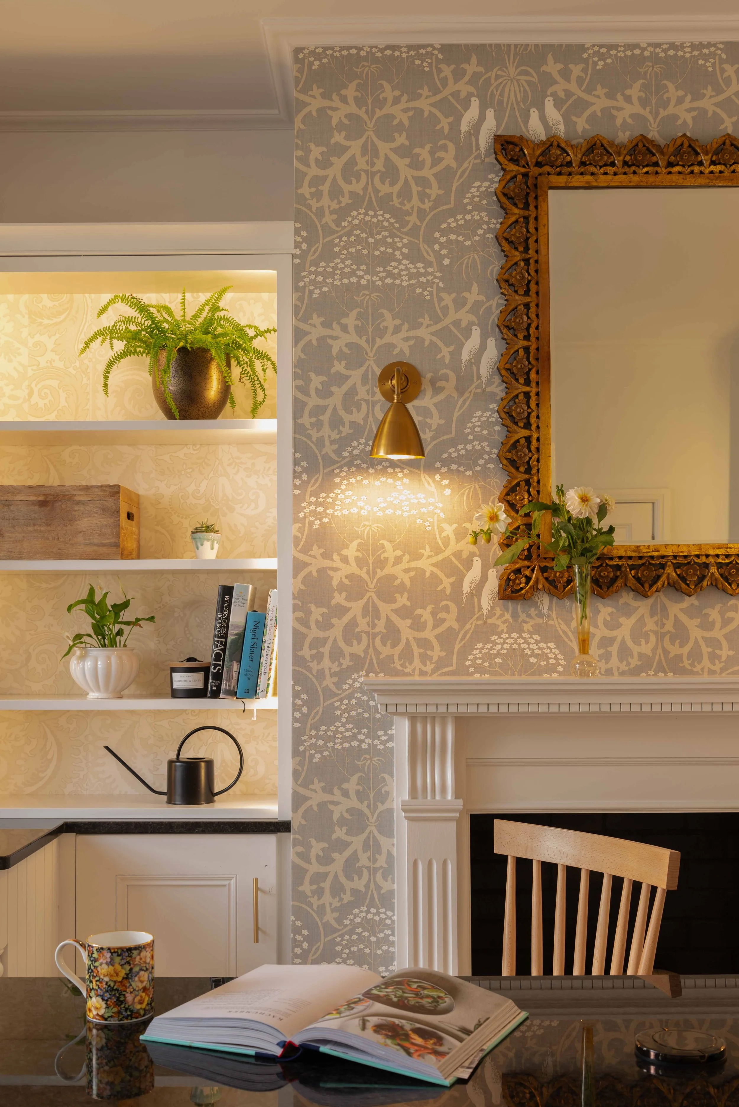 Sophisticated Georgian kitchen corner with decorative fireplace, bespoke shelving, brass lighting, and layered traditional interior styling.
