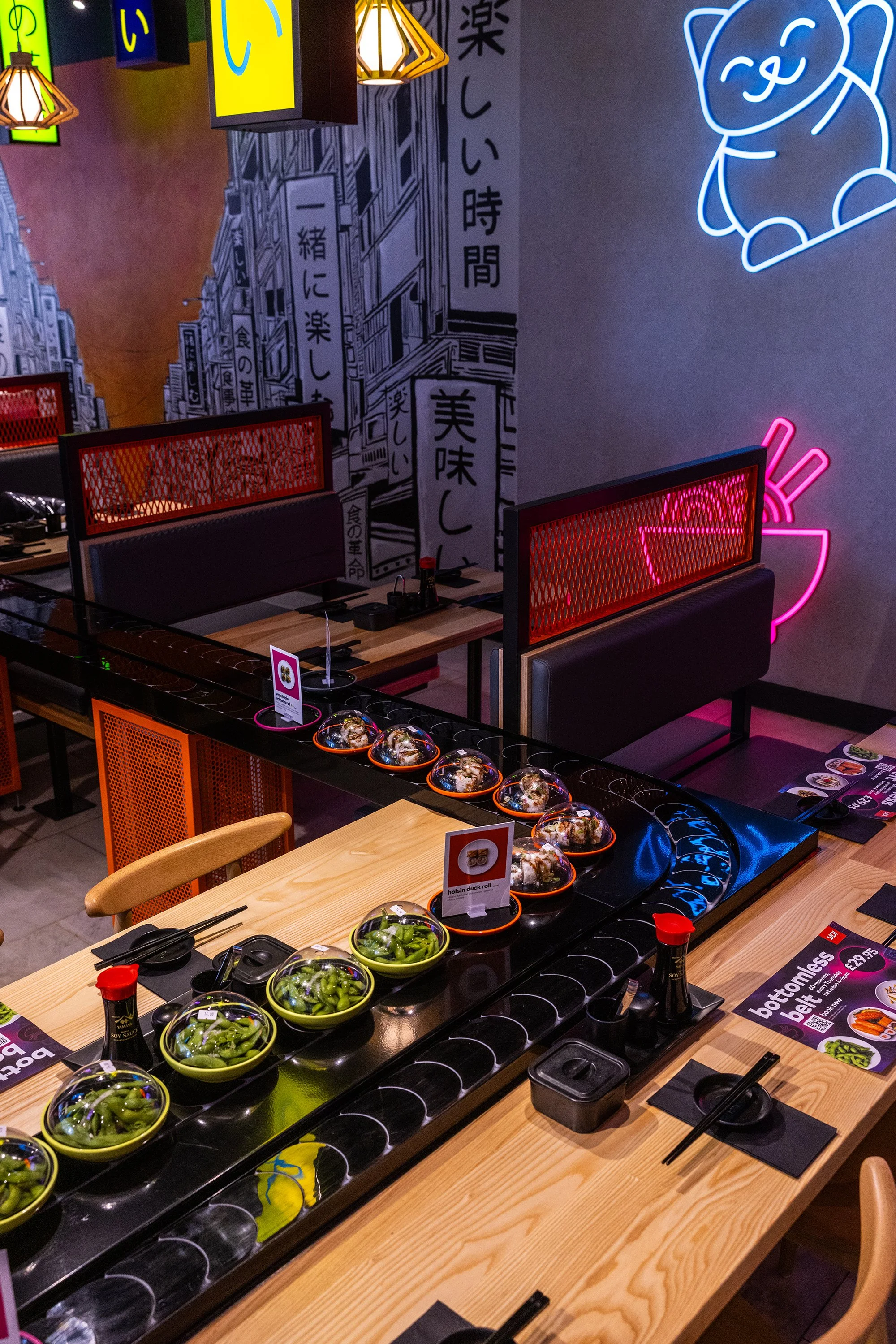 Contemporary YO! Sushi Stratford restaurant interior with conveyor belt dining, neon signage, and vibrant Japanese-inspired decor in London.