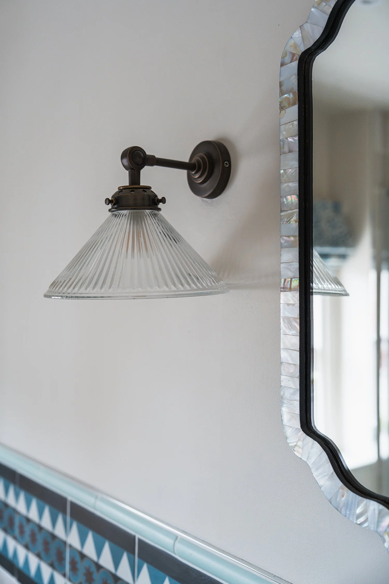 Vintage-style wall light and decorative mirror detail in a thoughtfully curated townhouse bathroom with artisan-inspired finishes.