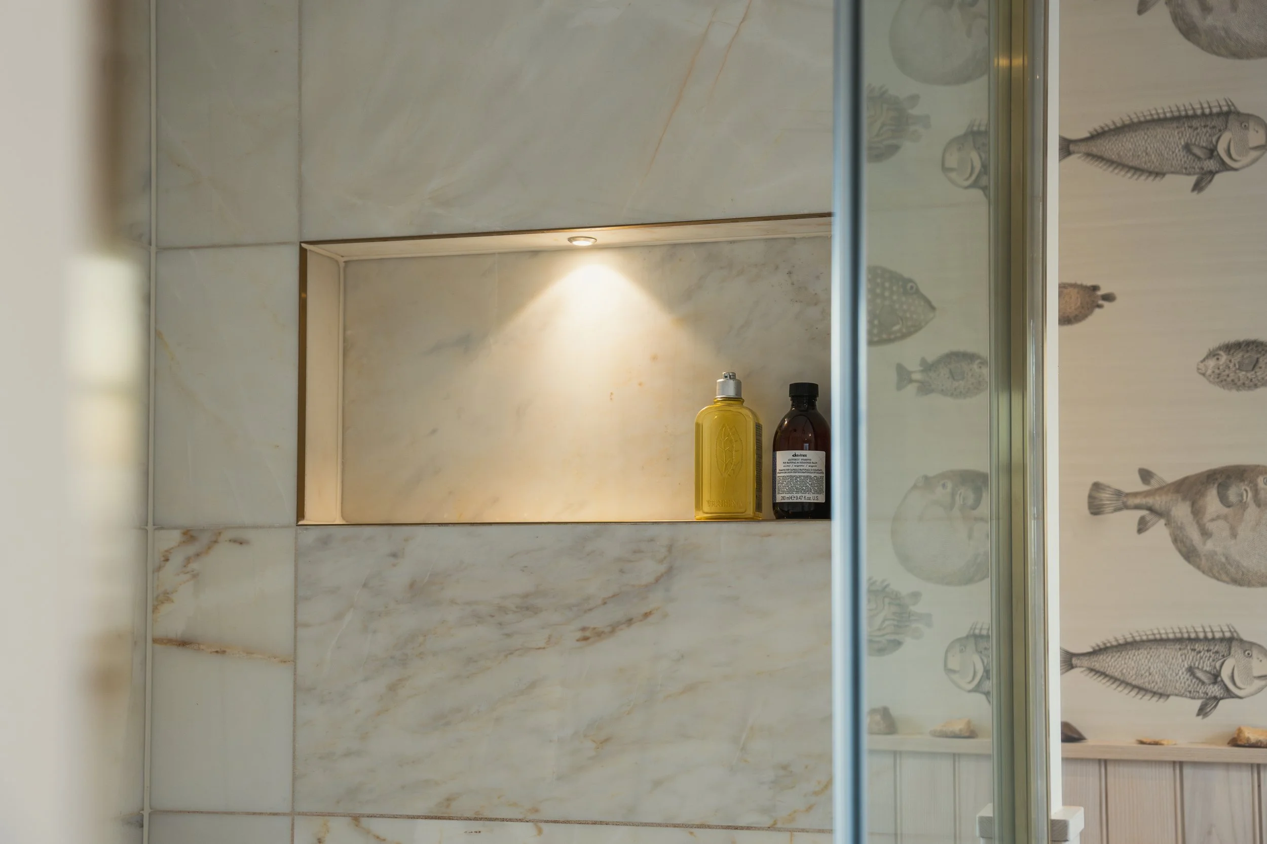 Luxury townhouse shower room with marble wall niche, soft ambient lighting, and curated bathroom styling blending timeless elegance with contemporary design.
