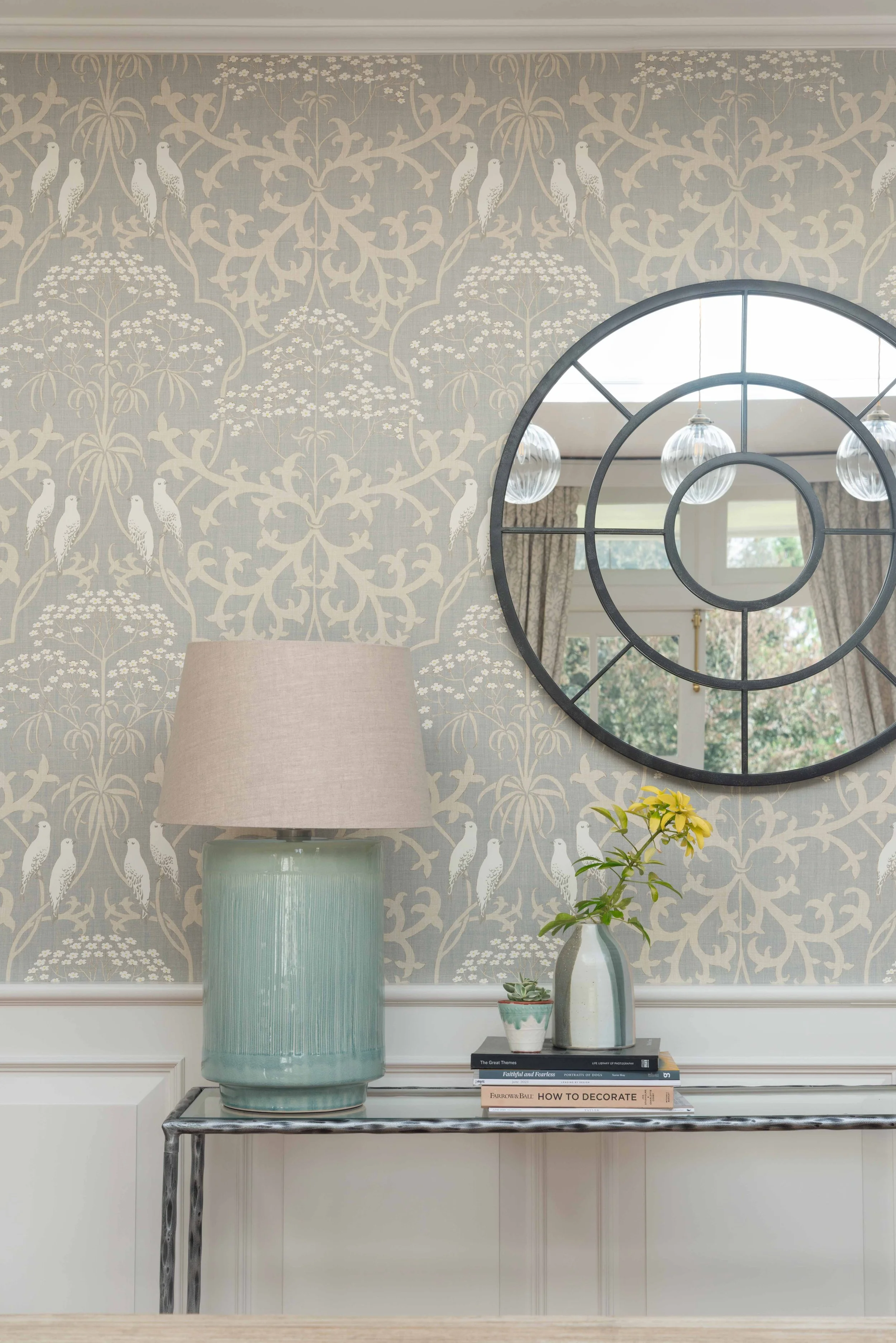 Classic country home interior with statement round mirror, marble console table, and delicate botanical wallpaper in a refined Georgian setting.