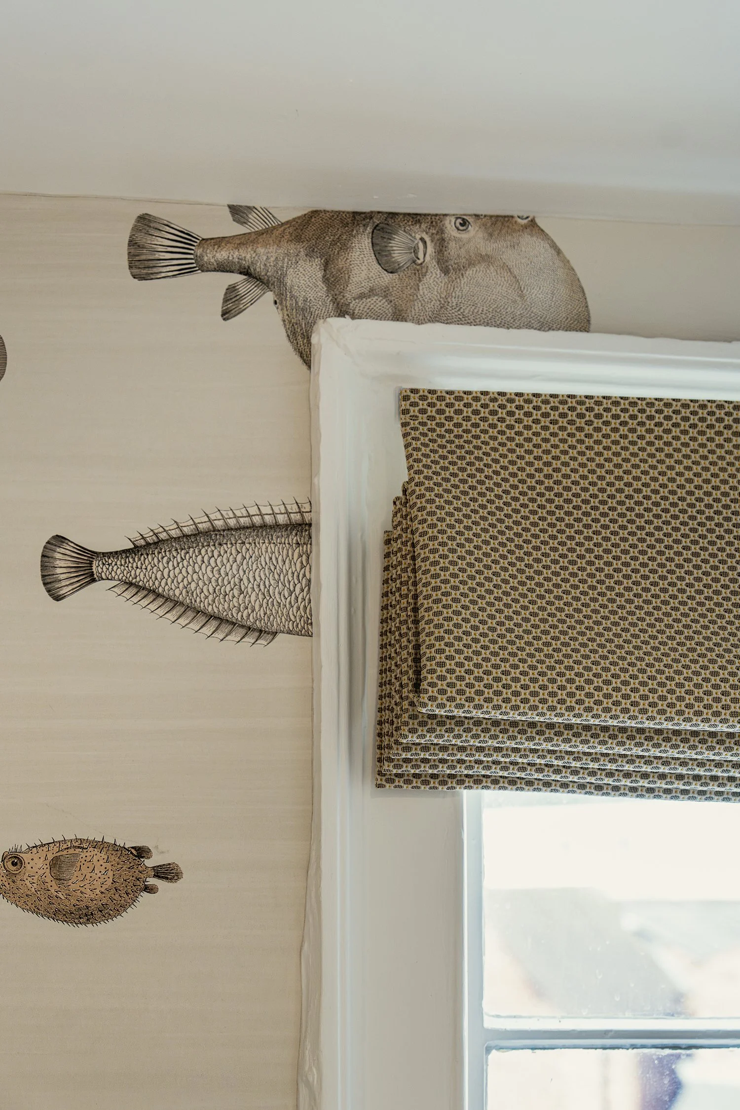 Decorative fish wallpaper and woven Roman blind detail adding warmth, texture, and personality to a thoughtfully designed shower room interior.