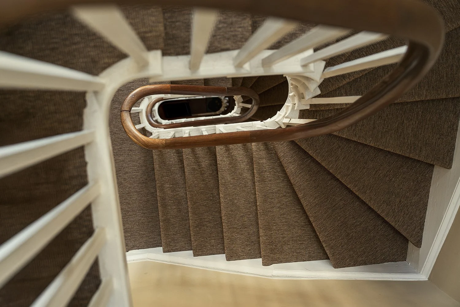 Original townhouse staircase with curved timber handrail and textured stair runner, celebrating the craftsmanship and character of a historic hallway interior.
