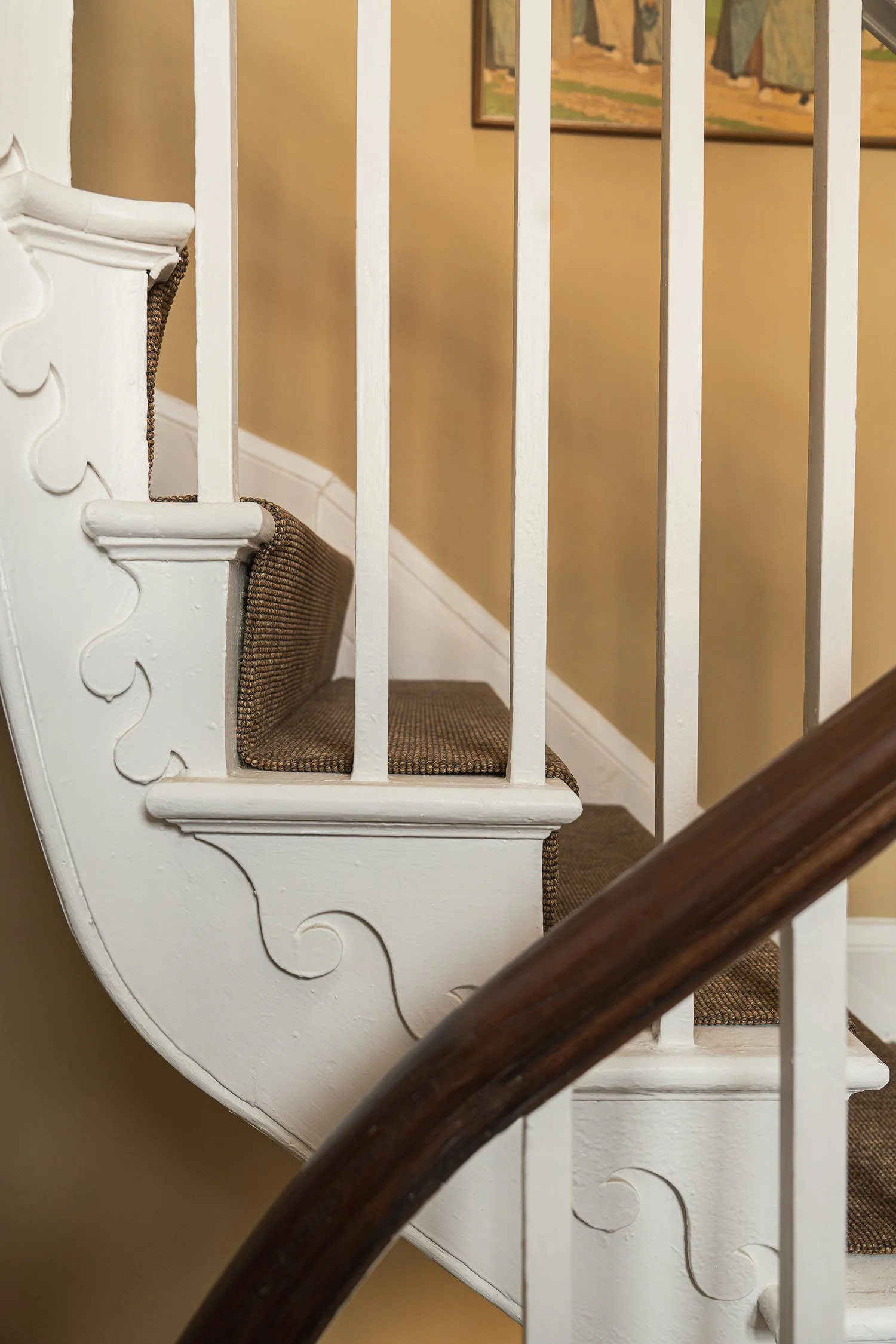 Original townhouse staircase with curved timber handrail, painted spindles, and soft neutral tones celebrating period architectural character.