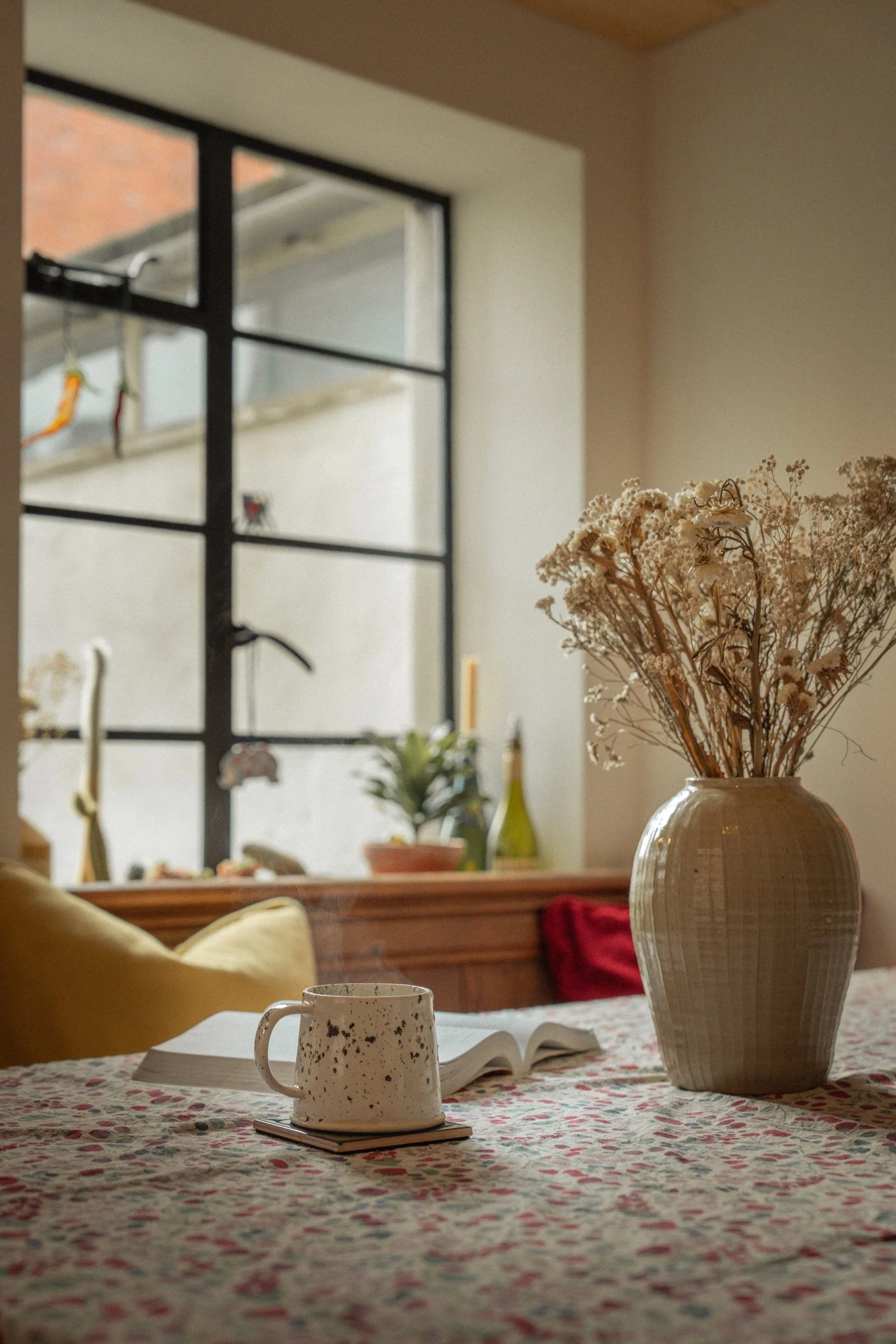 Softly styled dining nook with black-framed windows, layered textiles, and artisan ceramics in a warm Edwardian townhouse interior.