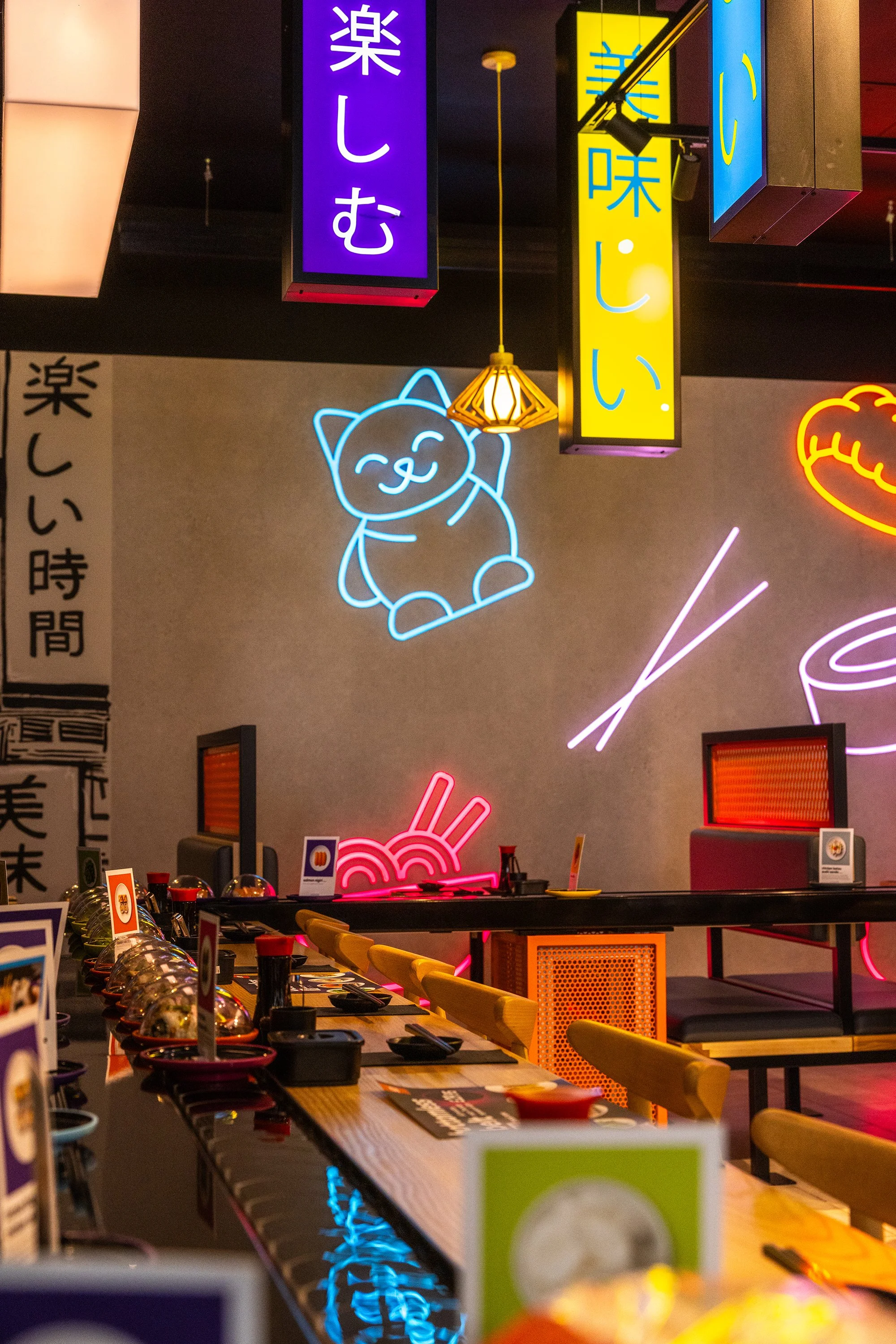 Modern sushi bar seating at YO! Sushi Stratford featuring colourful neon lighting, contemporary interiors, and urban Japanese design influences.