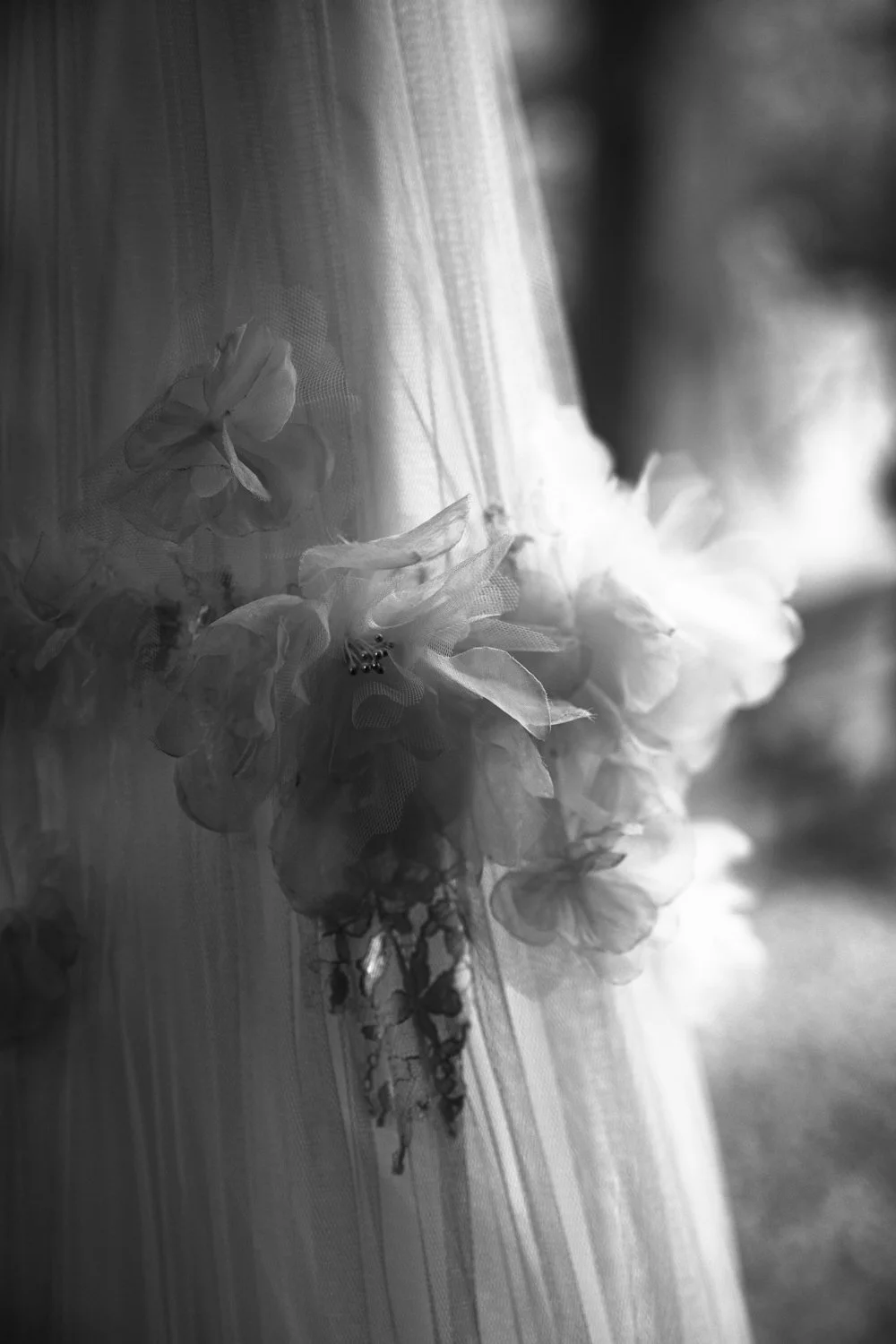 Close-up of a wedding dress with embroidery and floral appliqué details on tulle fabric, in black and white.
