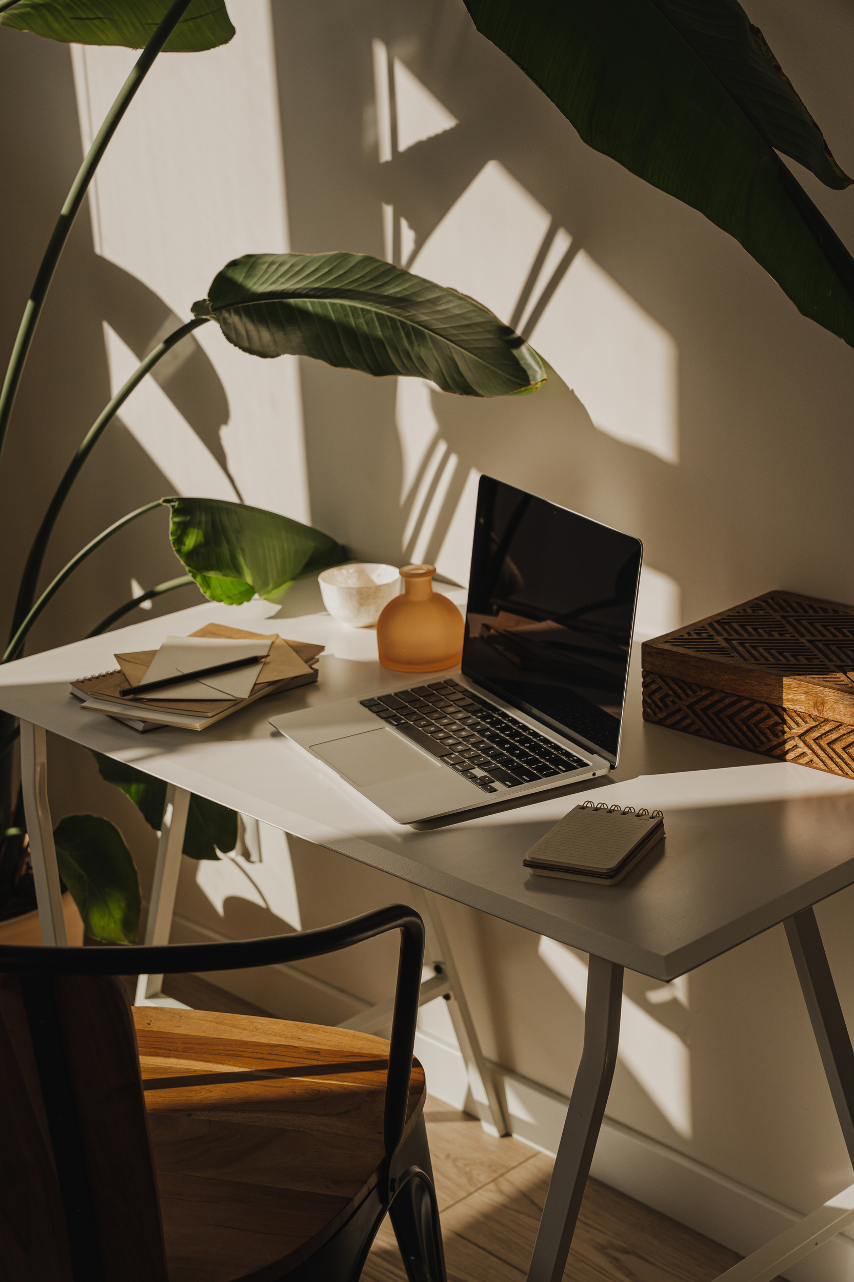 A desk with a laptop, note book, pen and plant