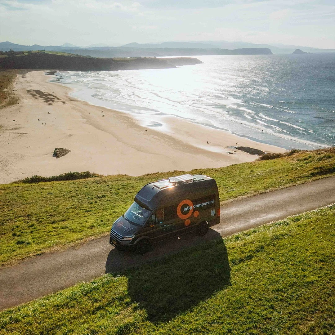 Campain shot for campervan rental company of a van driving along the northern spain coast drone photo