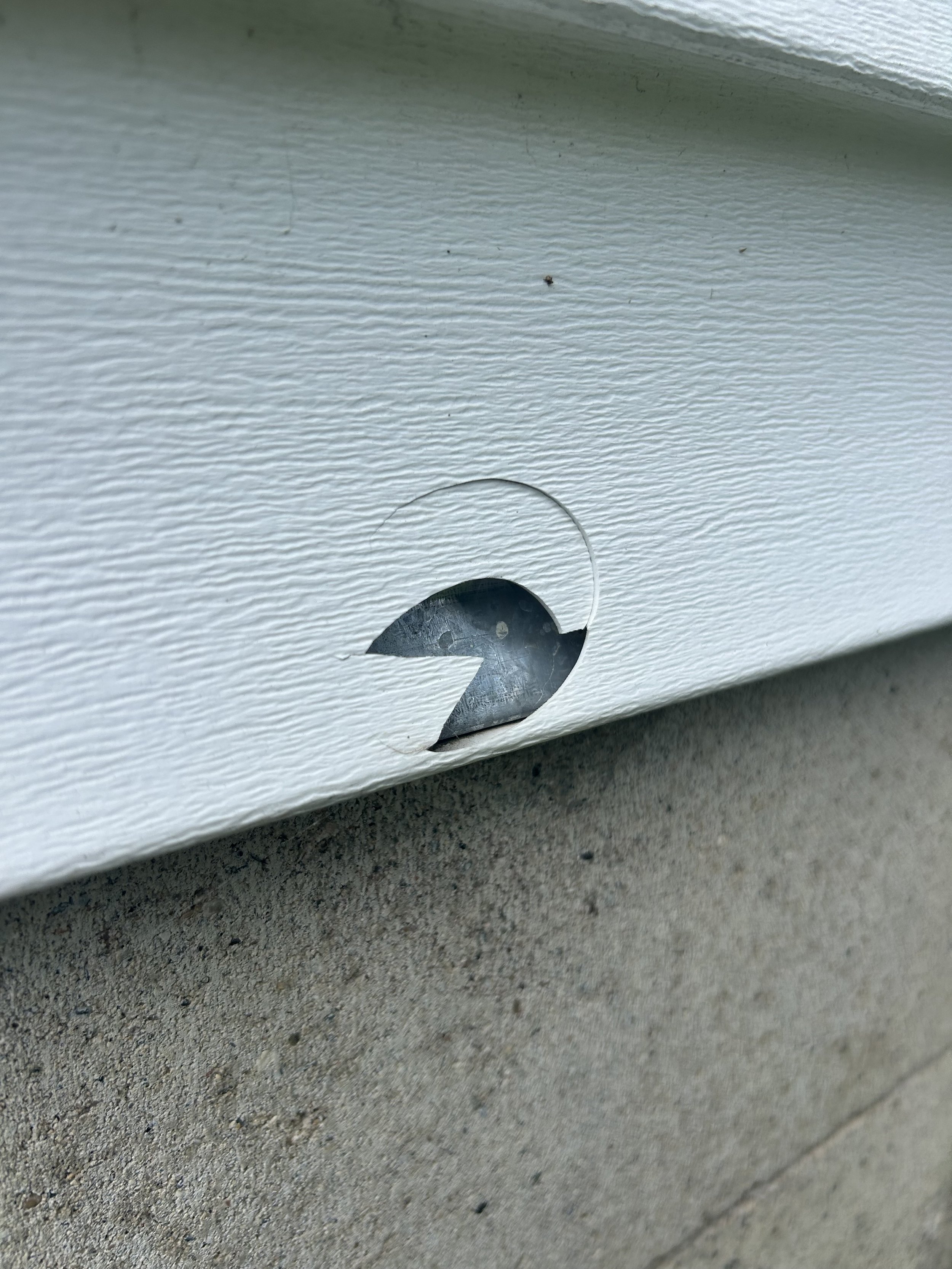 A piece of broken siding with a large gouge in it that resembles the number 2 or Pac-Man