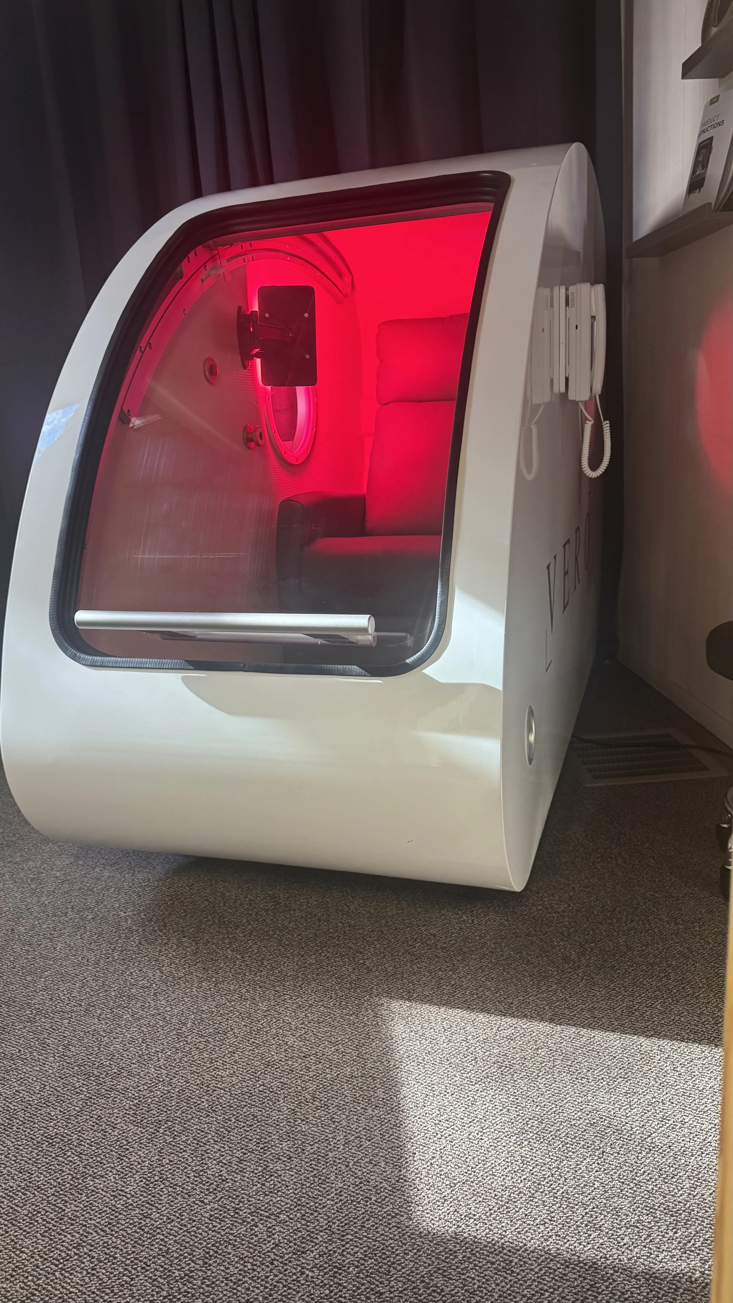 A soldier is lying inside a submarine, being attended to by a nurse or doctor. The person is lying on a bed, and the medical professional is crouching beside them, holding their hand and checking their condition.