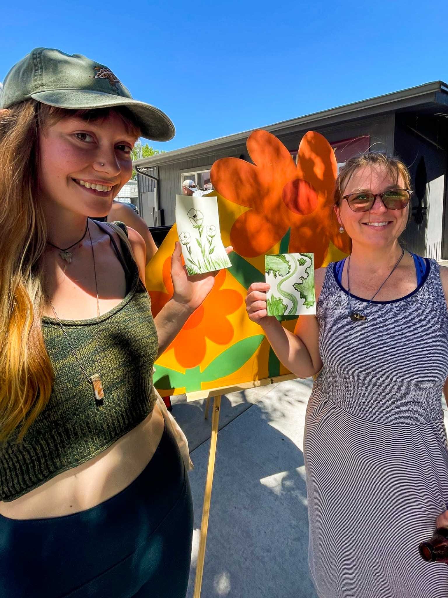 Two people holding up watercolors made from algae