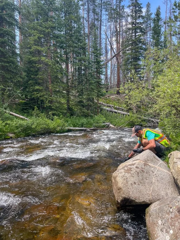 field scientist taking post-fire water quality samples from the poudre river