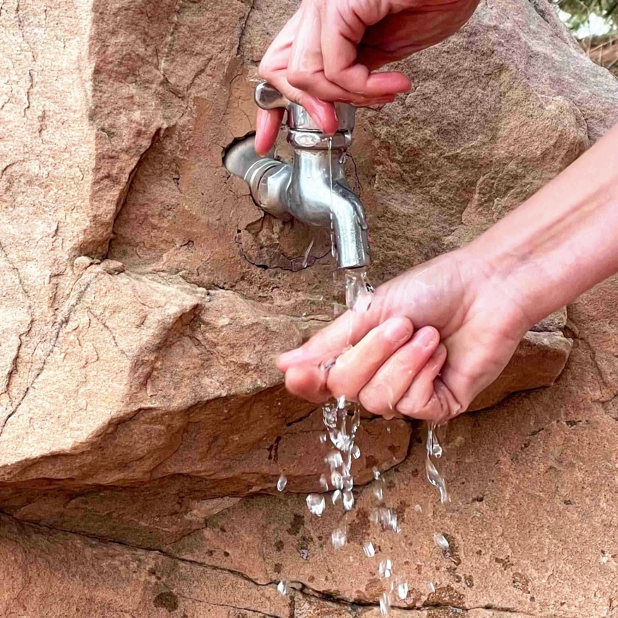 water from faucet coming out of a rock in Bryce Canyon National Park onto a hand beneath