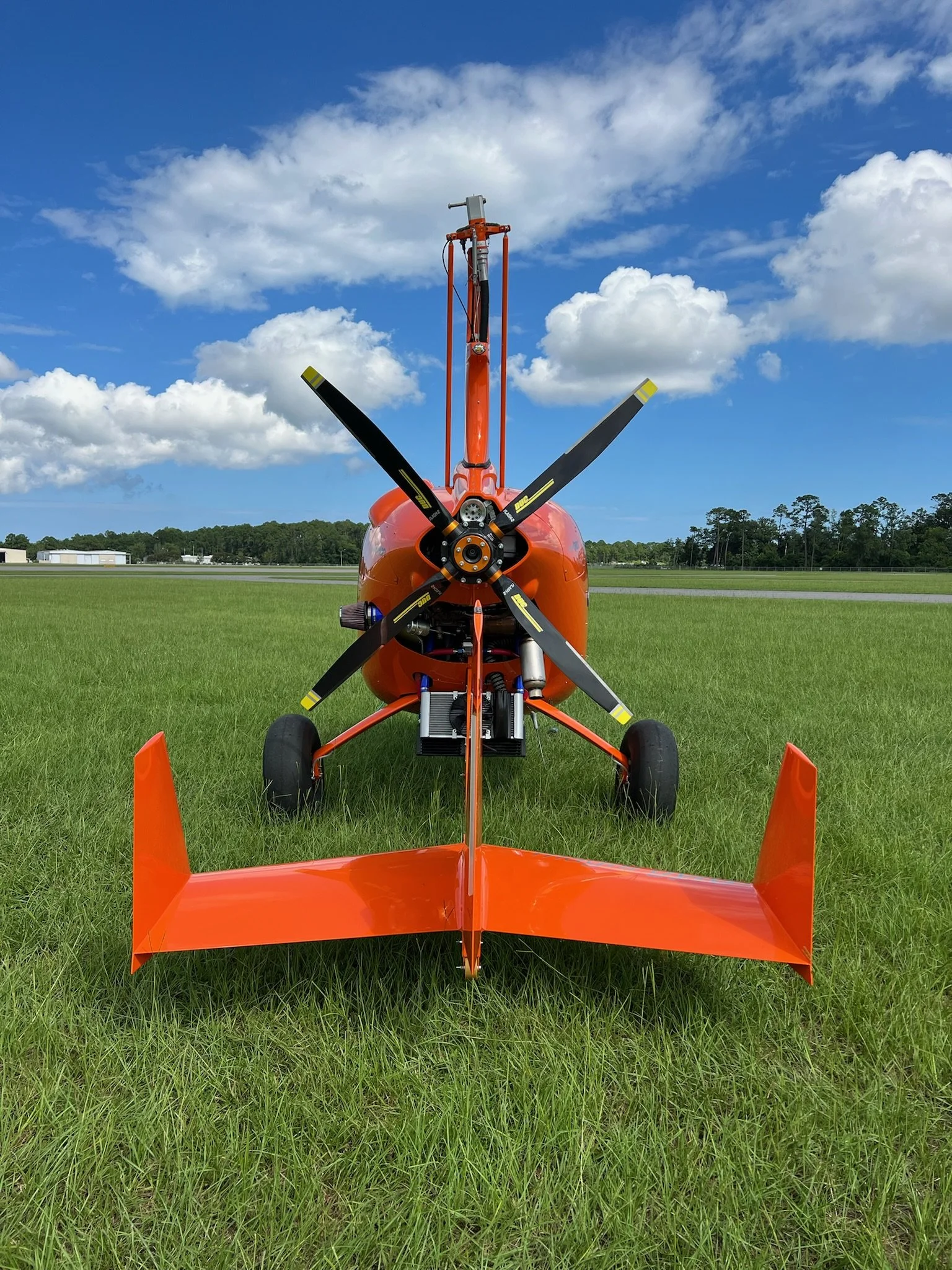 Orange M24 on a grassy field under a partly cloudy sky.