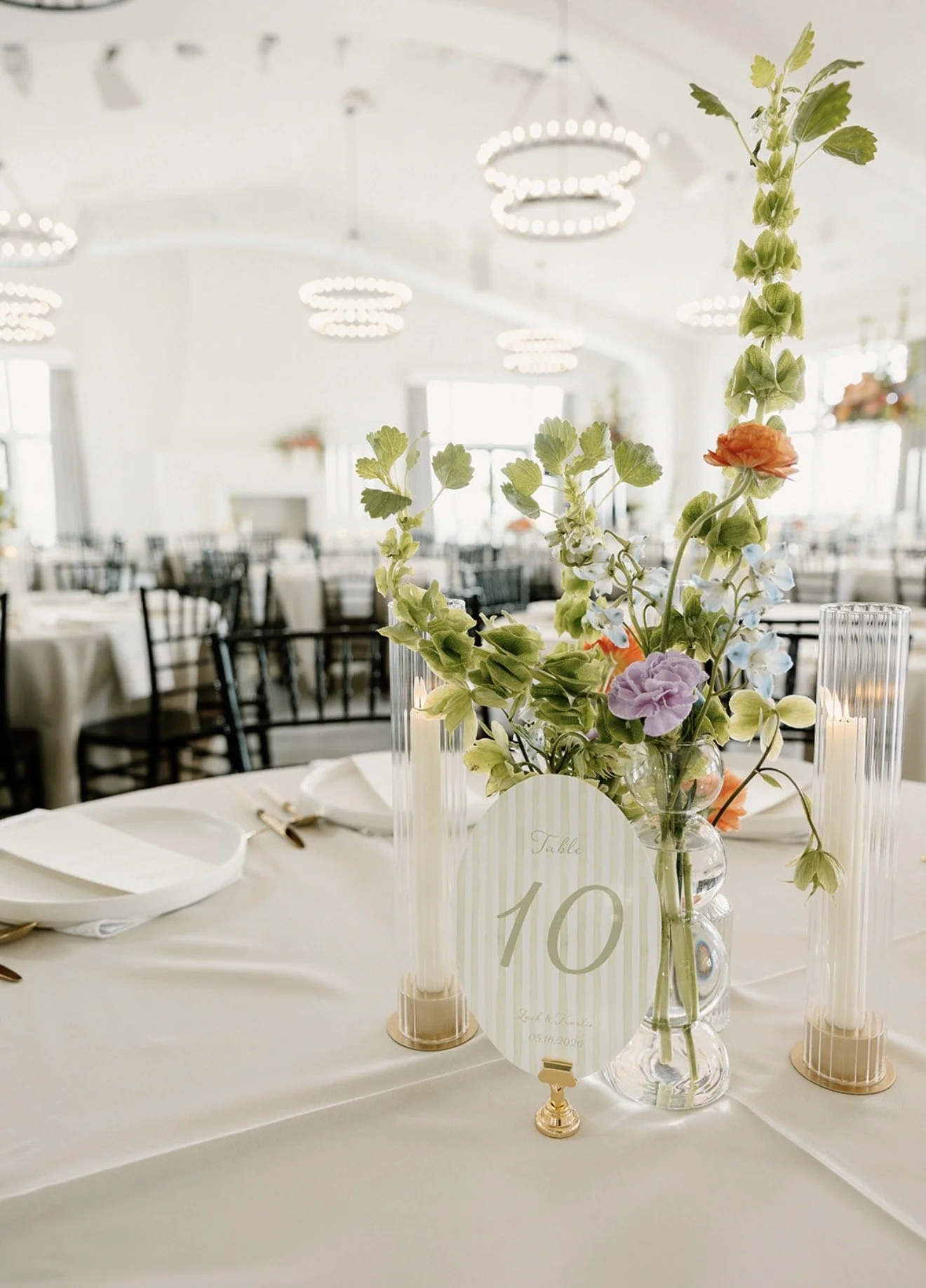 Elegant wedding reception table with colorful floral centerpiece, candles, place settings, and table number 10