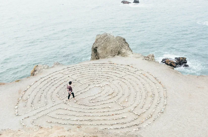 woman walking a maze of rocks on the beach
