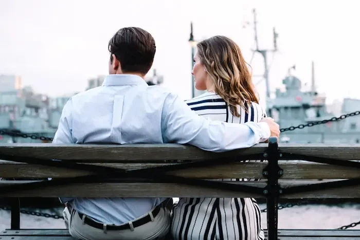 male-and-female-sitting-on-bench-by-ships