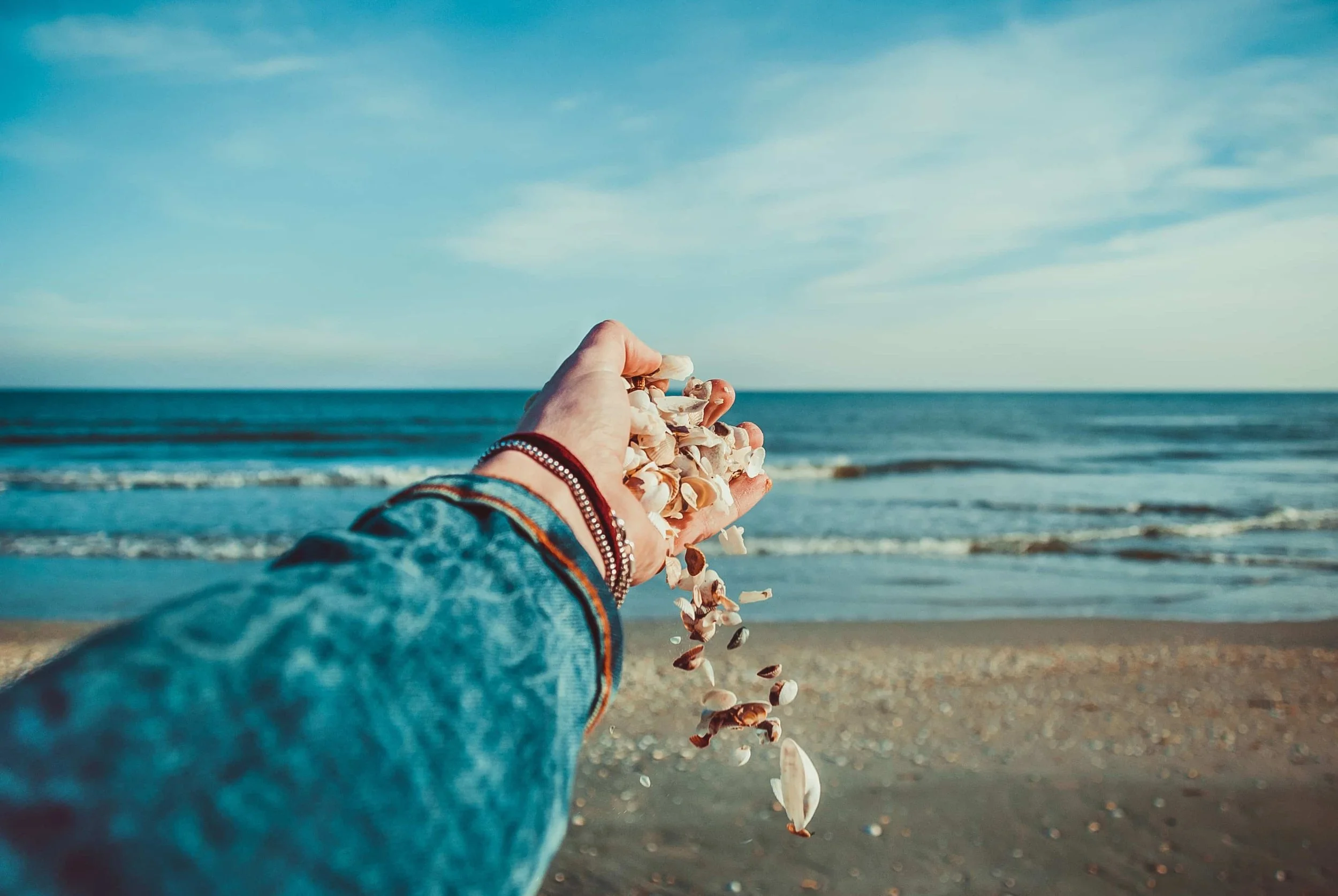 hand-dropping-and-sprinkling-shells-on-beach