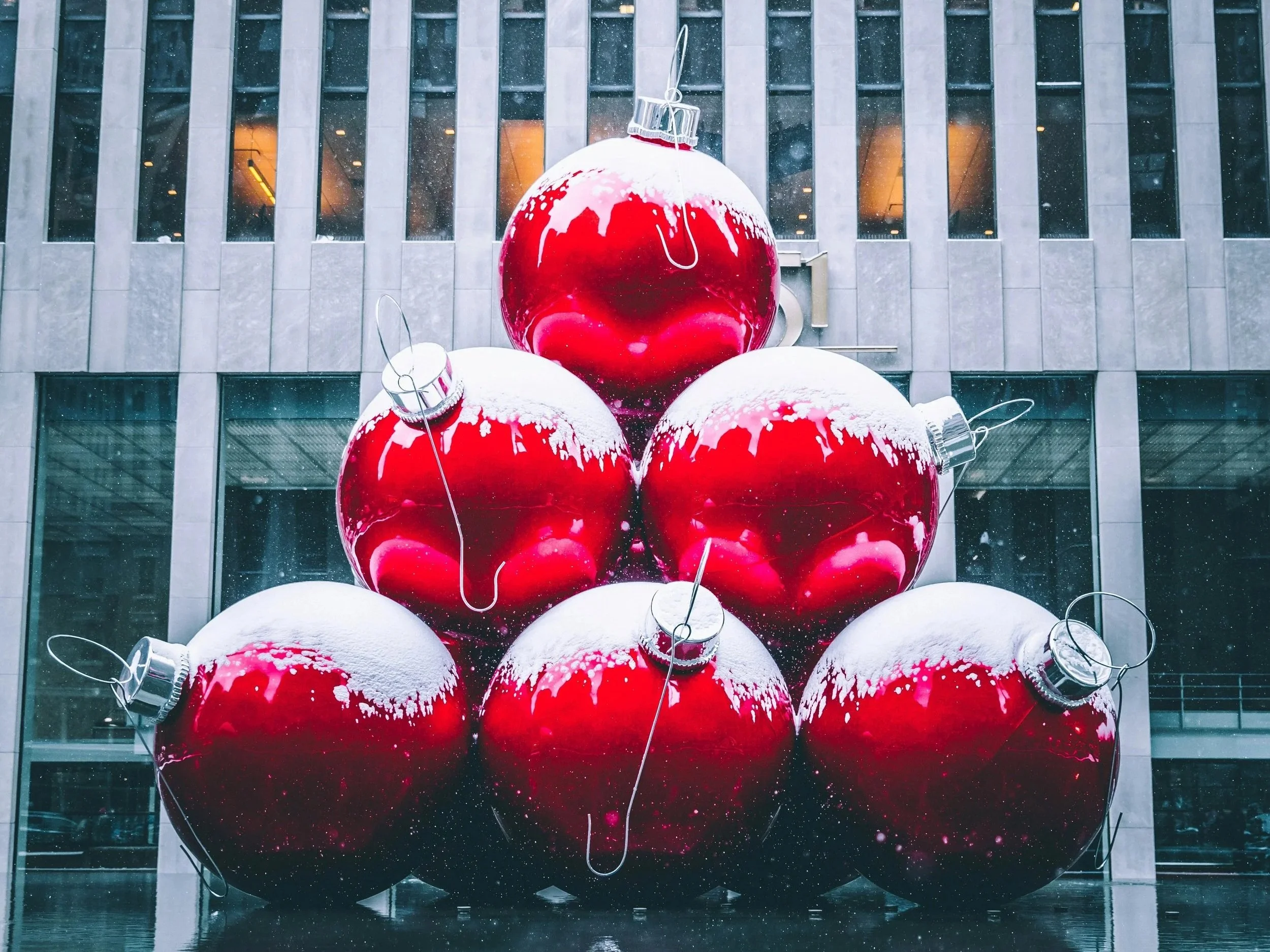 large-red-christmas-ornaments-piled-on-top-of-each-other-in-front-of-a-professional-building