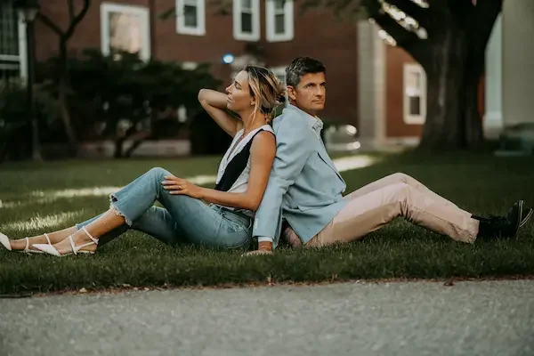 couple-sitting-back-to-back-on-grass