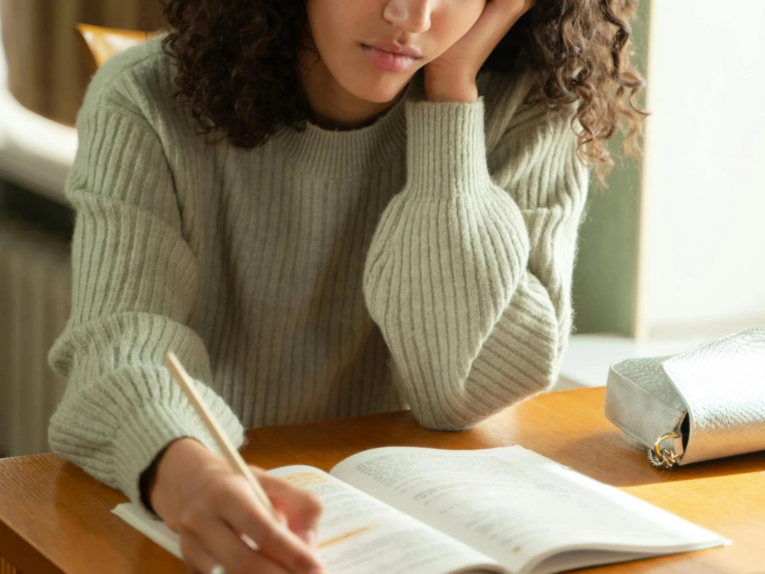 female-wearing-green-sweater-writing-in-book