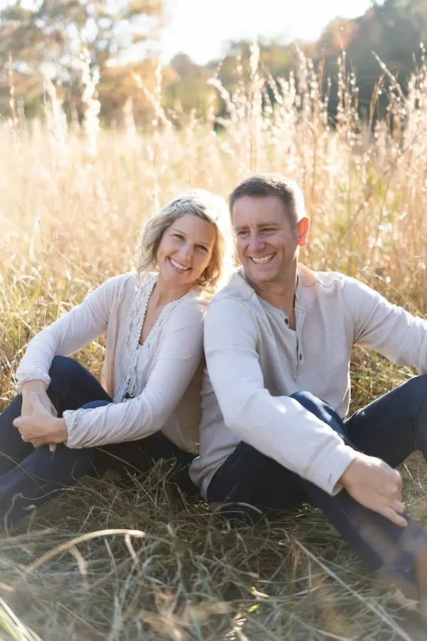 caucasian-couple-sitting-in-a-tall-grass-field-