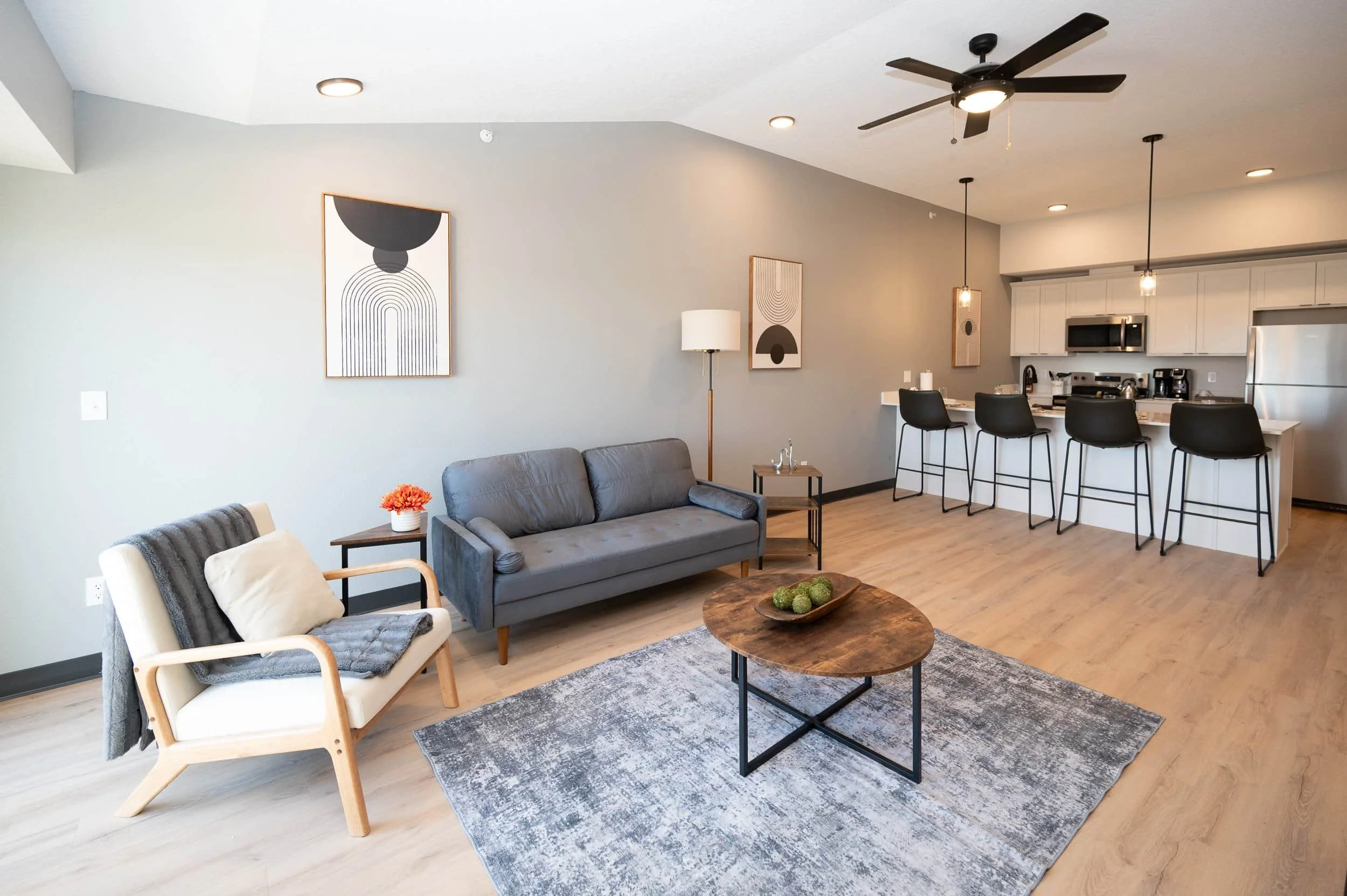 Modern open-concept apartments in Rochester feature minimalist decor, gray sofa, light wood floors, and pendant lighting.