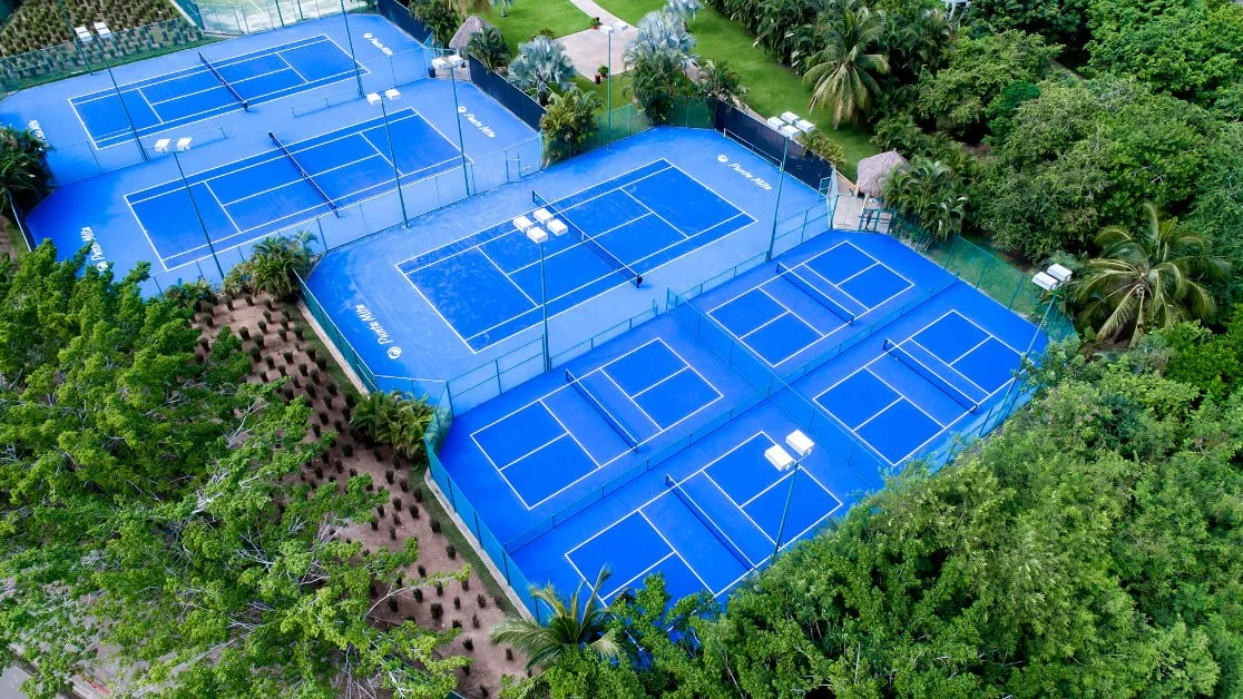 Aerial view of several blue tennis courts surrounded by trees.