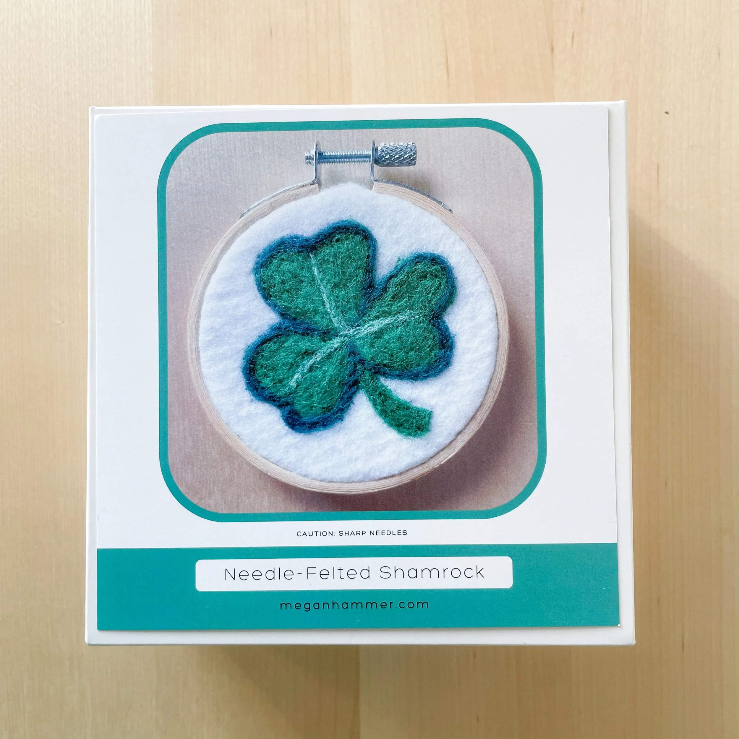 White box labeled Needle-Felted Shamrock Kit, showing a picture of felted art framed in an embroidery hoop.