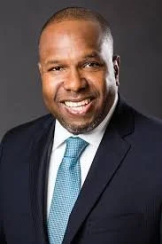 Smiling man in a suit and tie against a dark background
