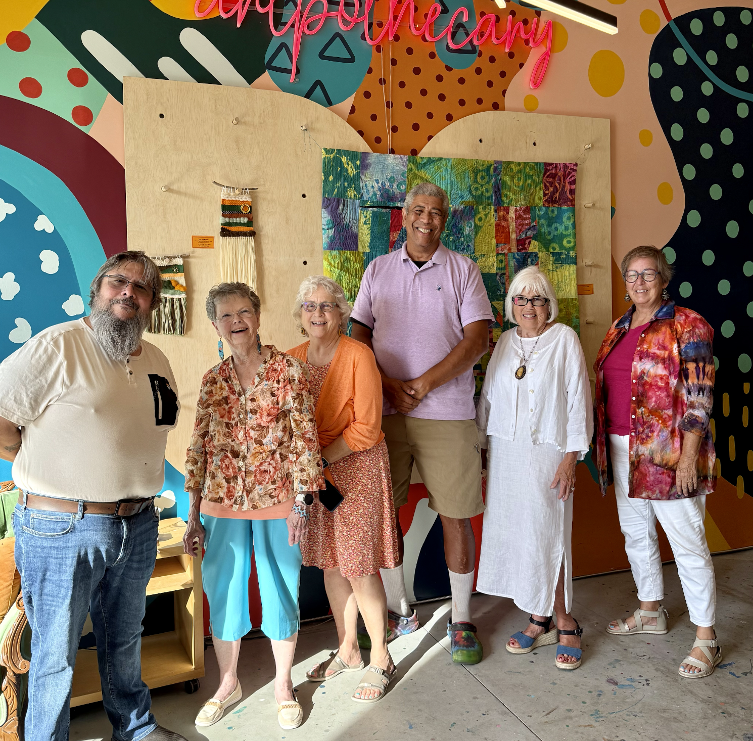 Group of people posing under "Creative Market" sign at an outdoor event with a barn in the background.