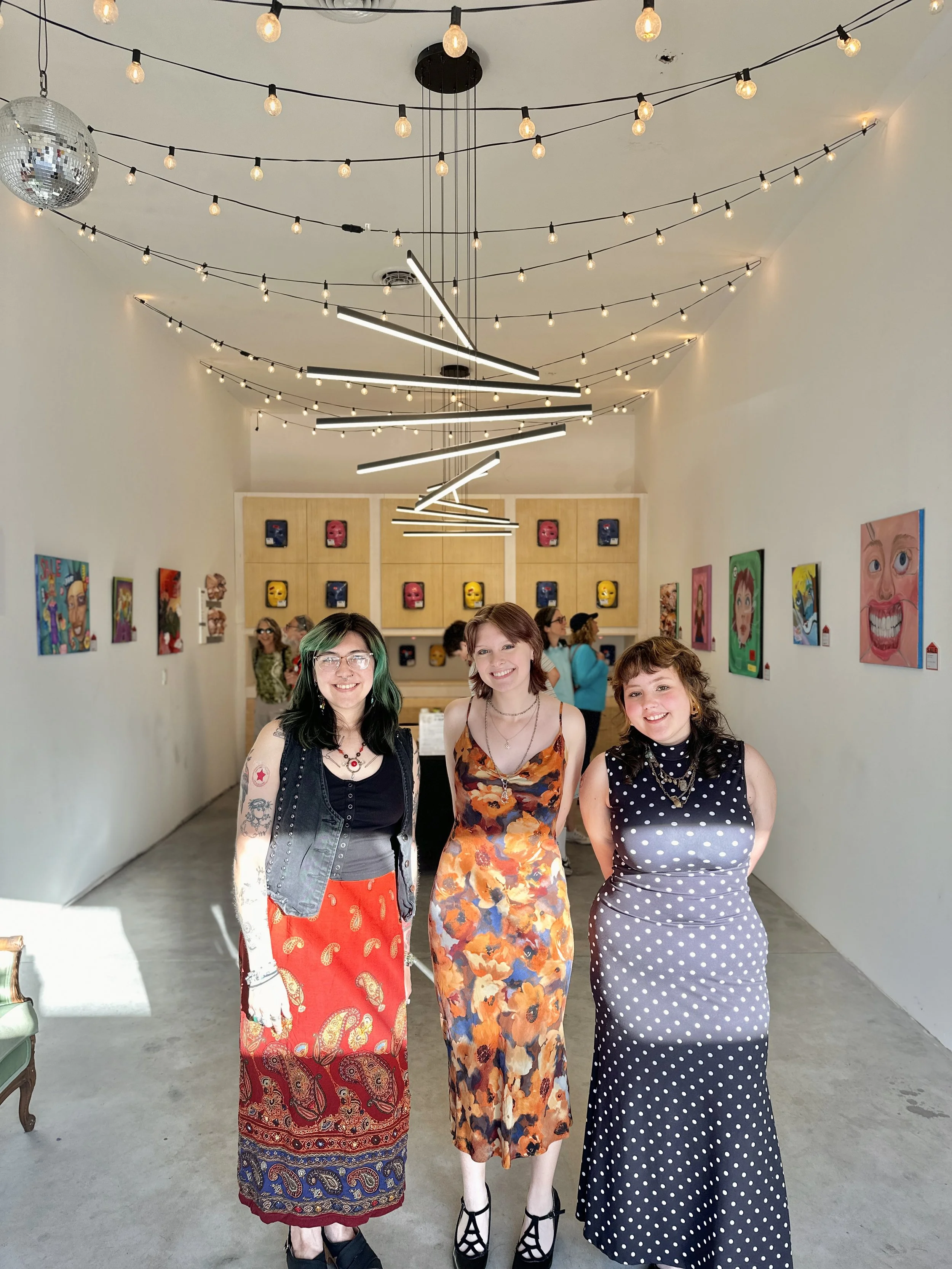 A group of people in a colorful, modern art studio with a mural wall, ceiling lights, and seating area.