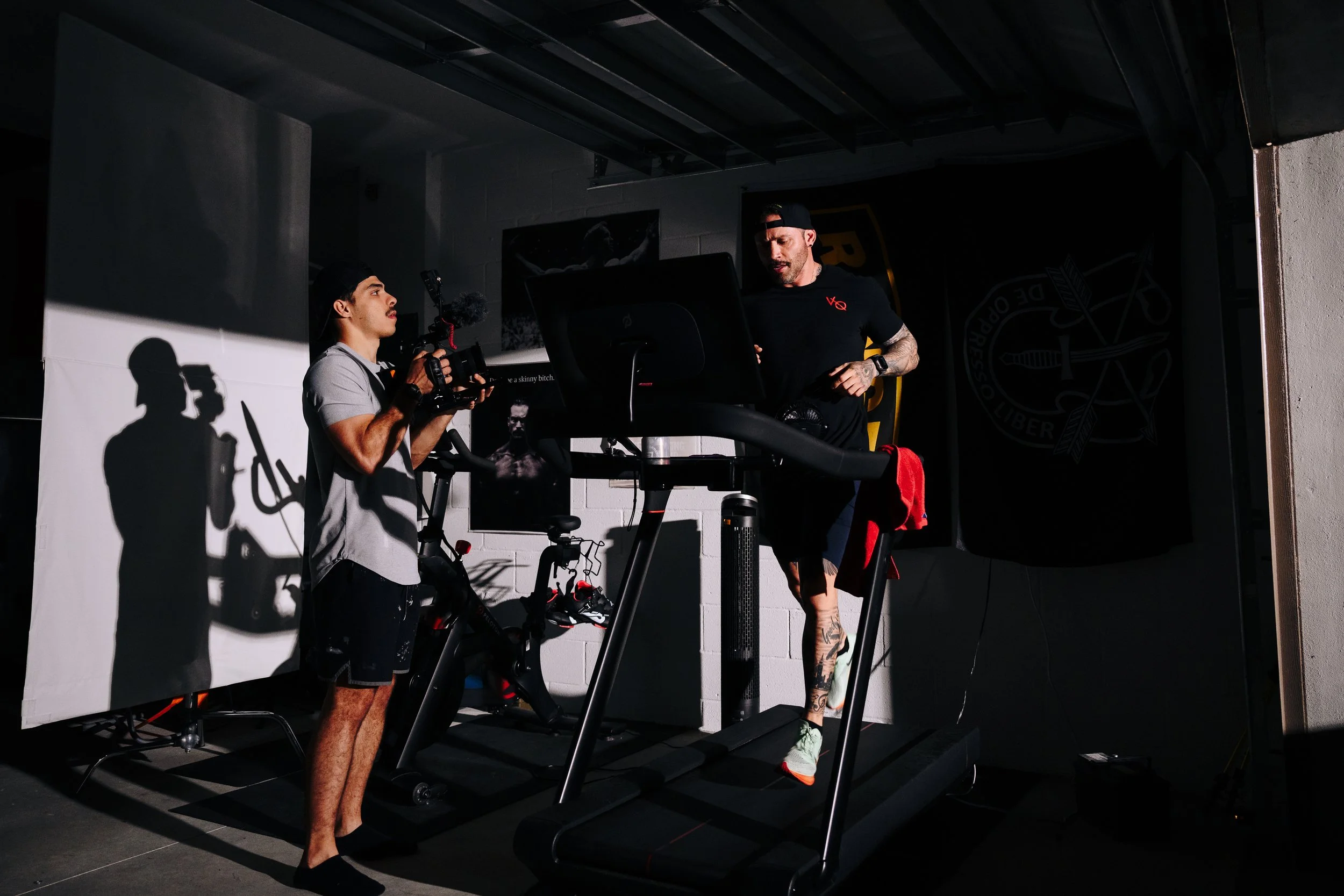 Carlos Contreras is running on a treadmill, being filmed by a filmmaker (Young Wild Dreams) with a camera in a gym.