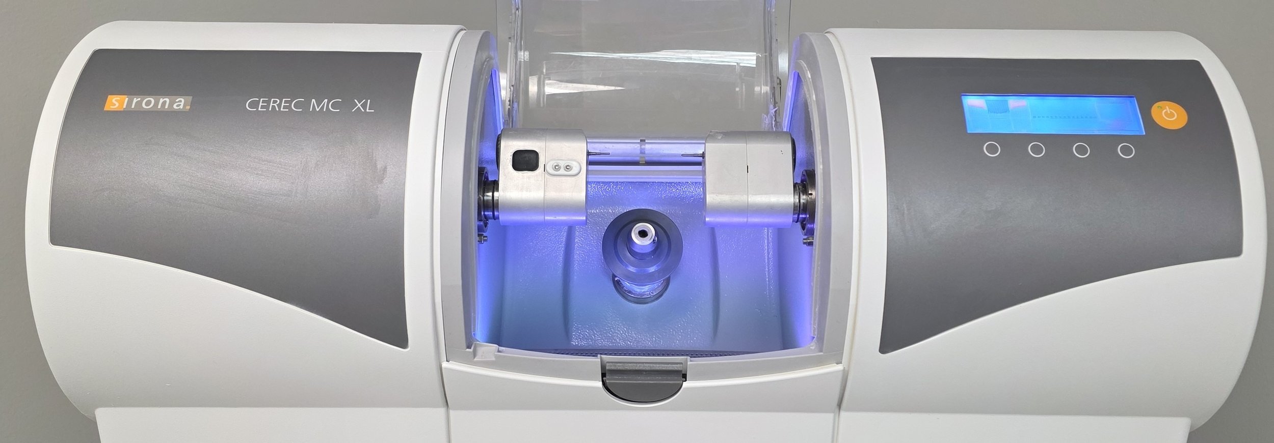 A scientific instrument with a digital display, buttons, and a central chamber with metallic components, labeled Sinon CEREC MC XL.