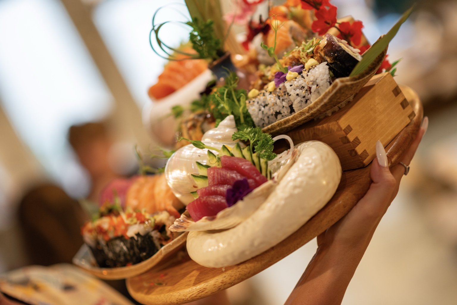 Sushi & Salad team member presenting a colourful sushi and sashimi sharing platter.