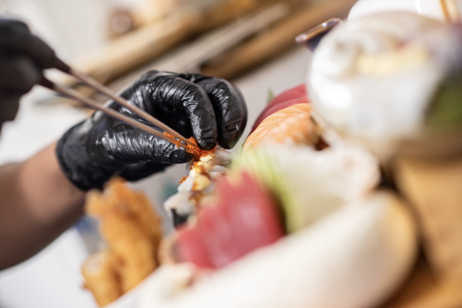 Chef assembling a fresh sushi and sashimi platter by hand.
