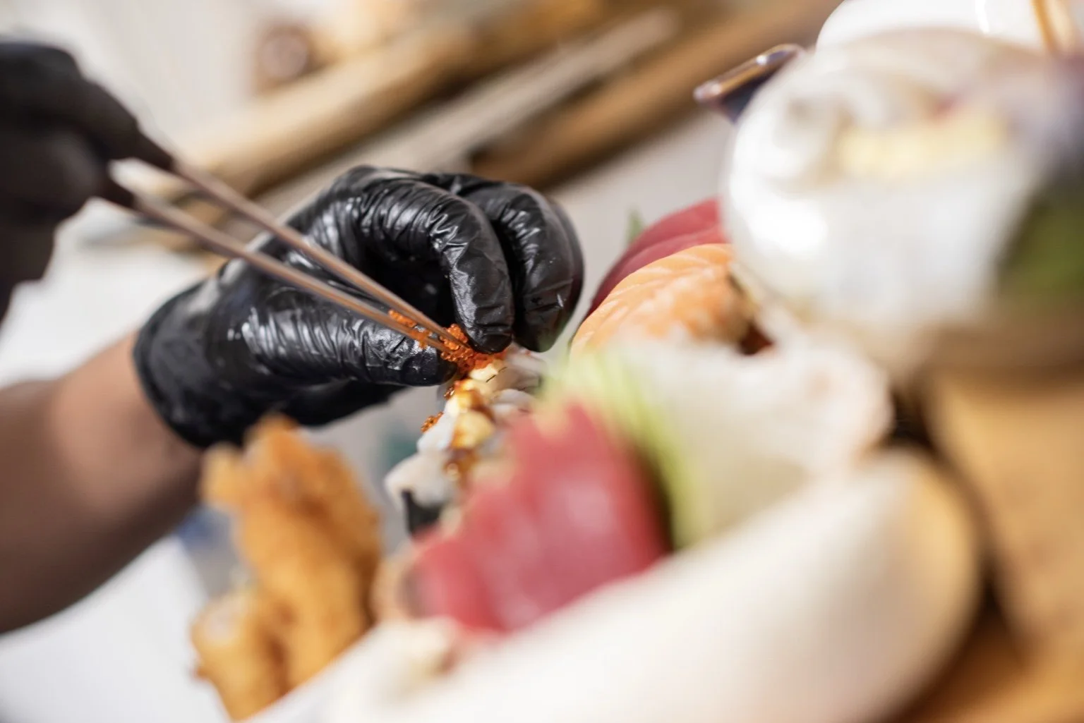 Chef carefully finishing an assorted sushi and sashimi platter.