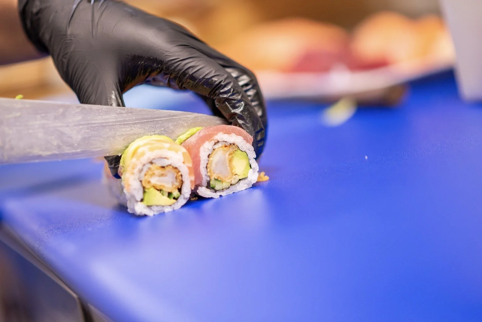 Sushi chef slicing freshly prepared rolls at Sushi & Salad.
